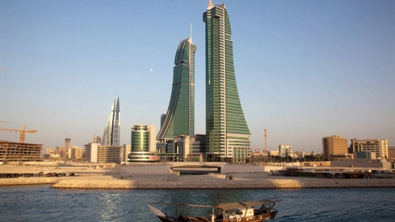 Bahrain 桌布 壁紙 — 標誌性的巴林世界貿易中心塔樓聳立在海濱，傳統獨桅帆船在黃金時段位於前景。