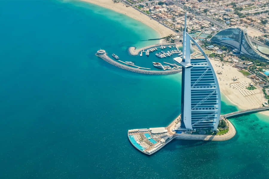 島嶼 桌布 壁紙 — 標誌性的帆形帆船酒店 Burj Al Arab Jumeirah 在沙漠島嶼上的鳥瞰圖，周圍是碧綠的海水。