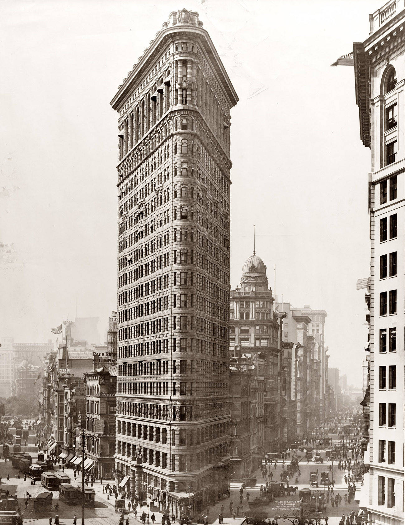 Flatiron Building 桌布 壁紙 — 標誌性的熨斗大廈在20世紀初繁忙的城市景觀中高聳，周圍有馬車和行人。