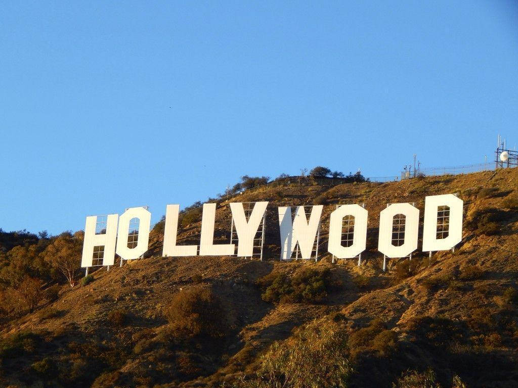 USA 桌布 壁紙 — 標誌性的白色好萊塢標誌在晴朗的藍天下，大膽地矗立在陽光普照的山坡上。