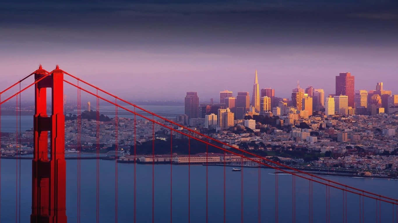 1366x768 San Francisco 桌布 壁紙 — 標誌性的紅色金門大橋在黃昏時分以紫色和橙色色調框住發光的舊金山天際線。