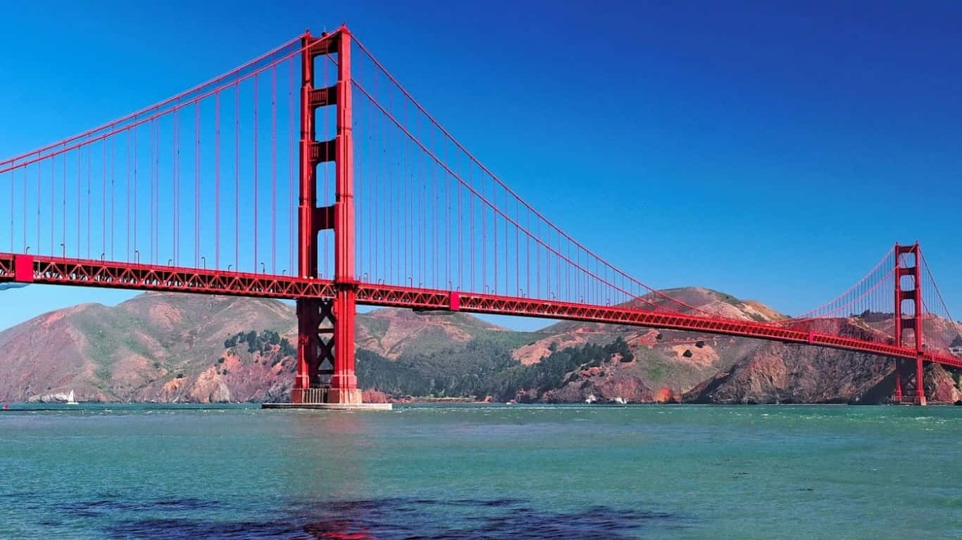 1366x768 San Francisco 桌布 壁紙 — 標誌性的紅色金門大橋橫跨在碧綠的海灣上，天空湛藍，遠山依稀可見。