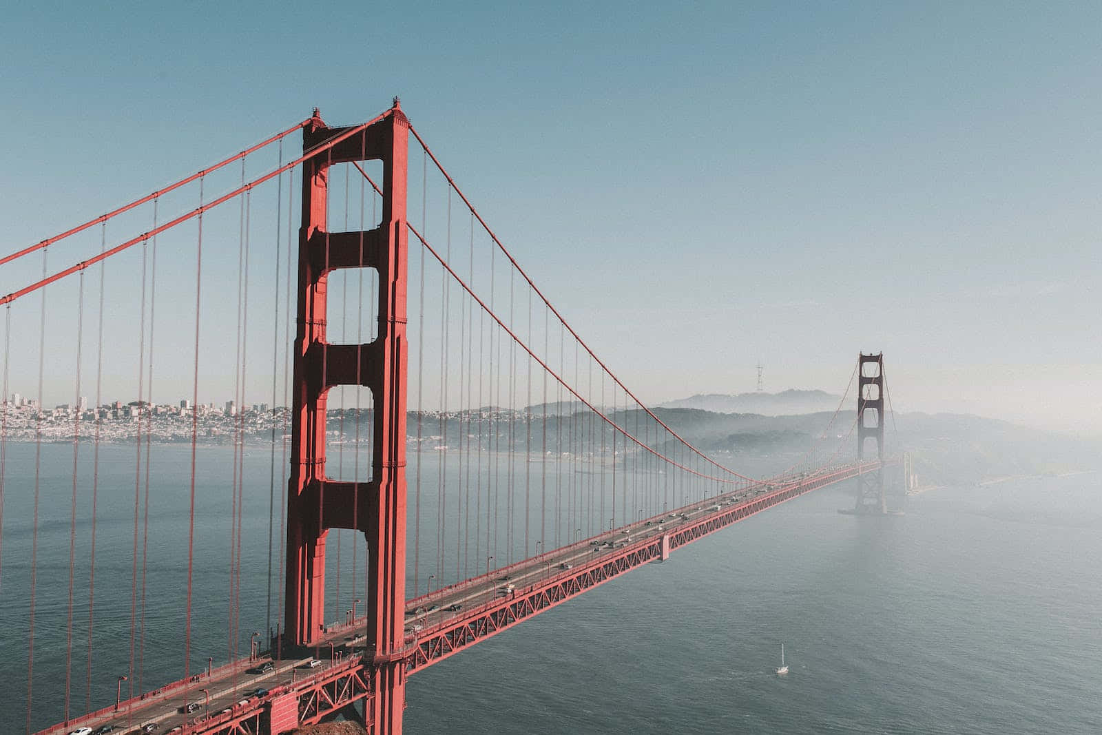 San Francisco Fog 桌布 壁紙 — 標誌性紅色金門大橋橫跨霧濛濛海灣的鳥瞰圖，背景是城市景觀。