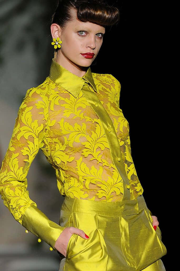 Yellow Fashion 桌布 壁紙 — 模特兒在伸展台燈光下自信地走秀，穿著大膽的黃色蕾絲上衣和相配的緞面褲。