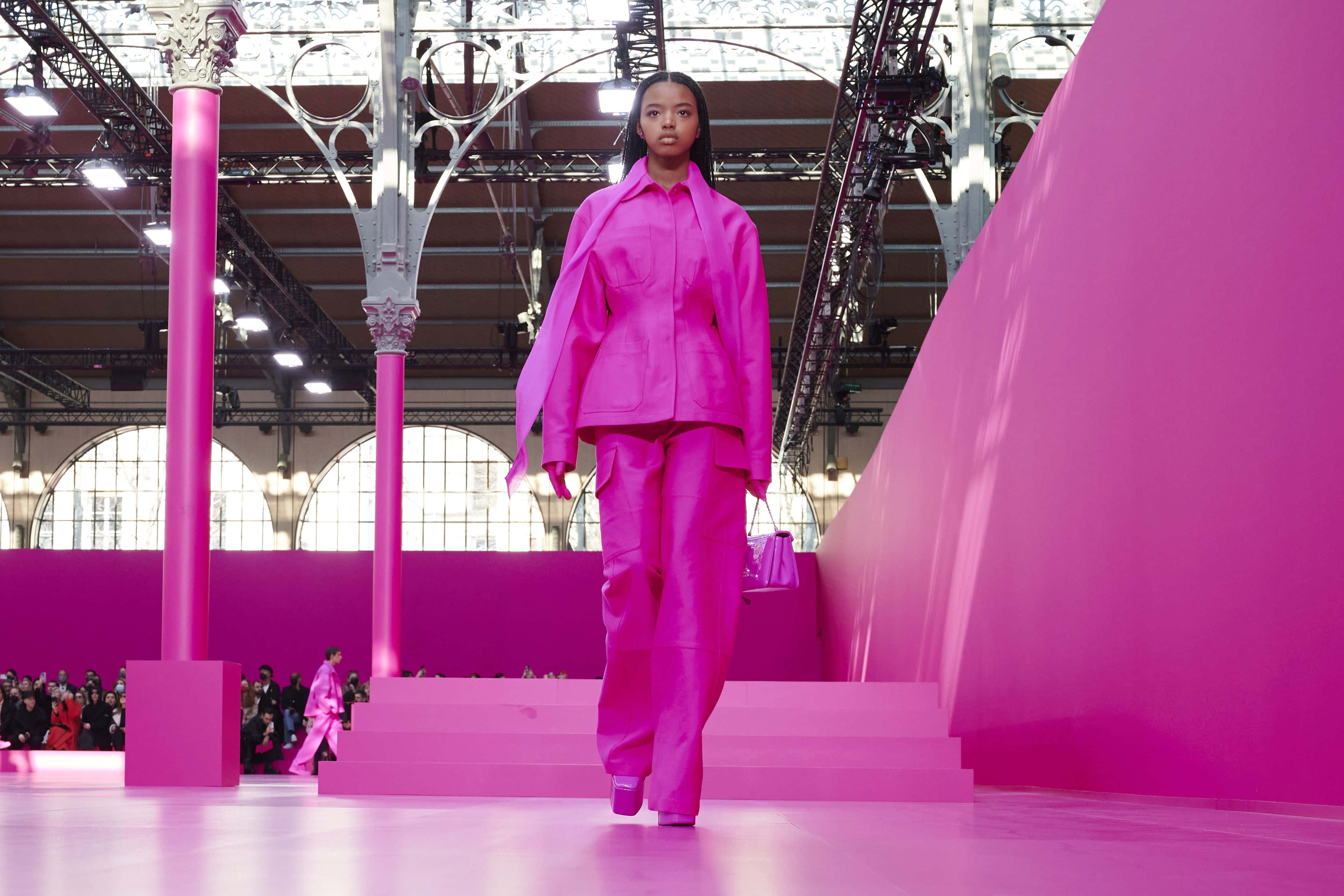 Pink Fashion 桌布 壁紙 — 模特兒在工業風格的玻璃天花板下，自信地走在充滿活力的粉紅色伸展台上。