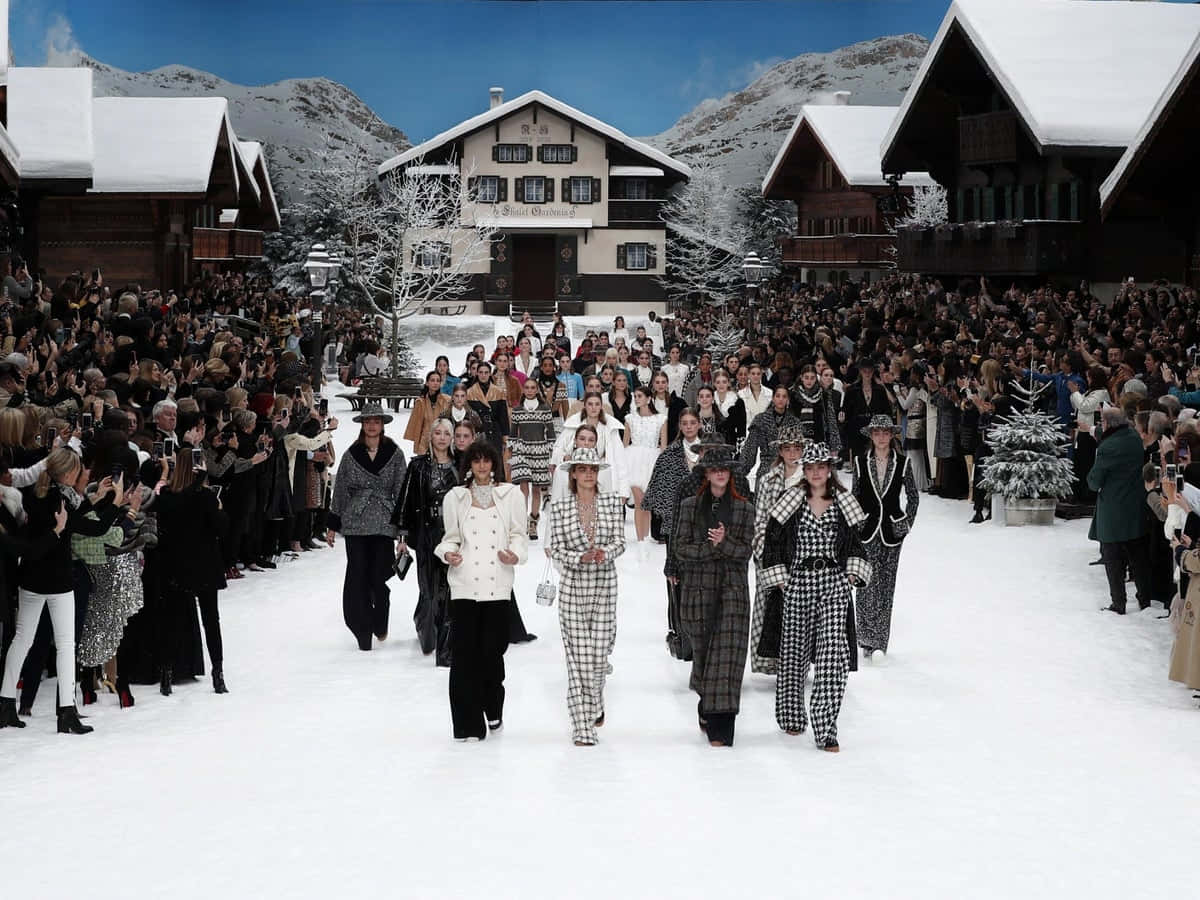 Runway 桌布 壁紙 — 模特兒在晴朗藍天下的山村，在歡呼的人群簇擁下走在雪地伸展台上。