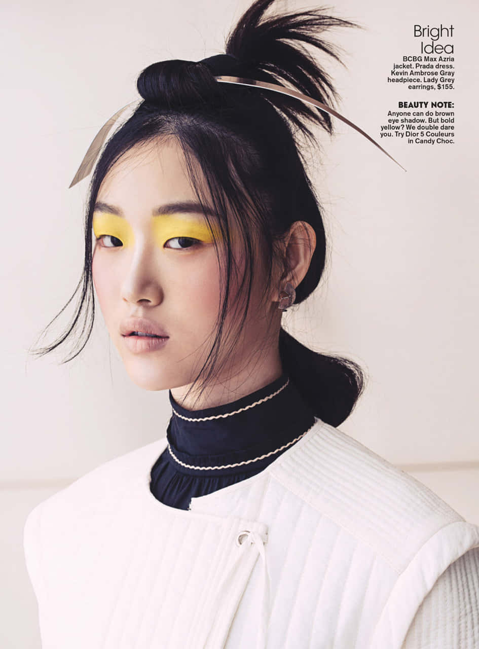 Pretty Girl 桌布 壁紙 — 模特兒帶有鮮明的黃色眼影和高馬尾，穿著白色羅紋上衣和黑色領子，背景為純色。