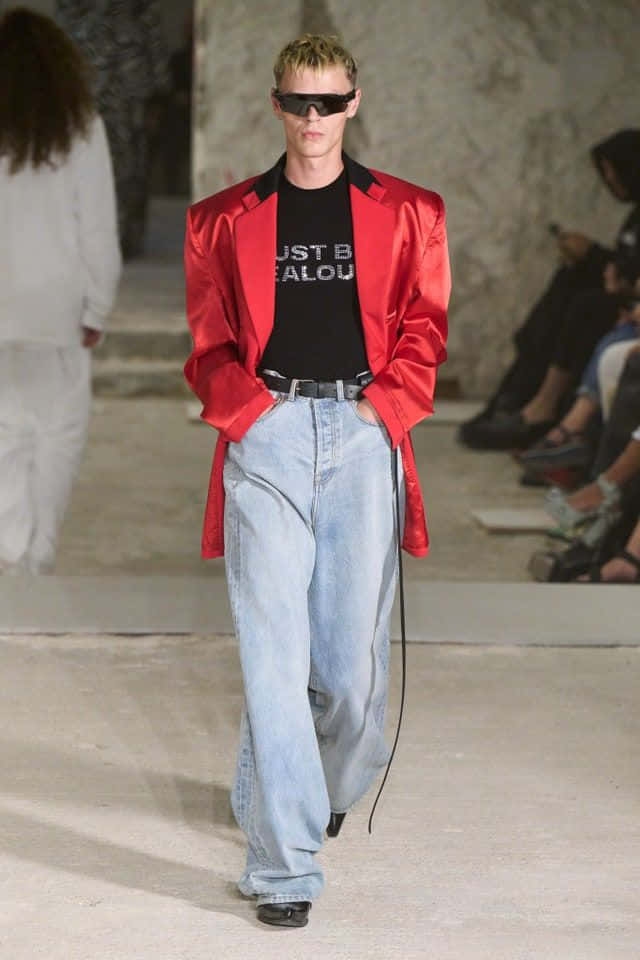 vetements 桌布 壁紙 — 模特兒穿著大膽的紅色緞面西裝外套、超大牛仔褲和黑色太陽眼鏡走秀。