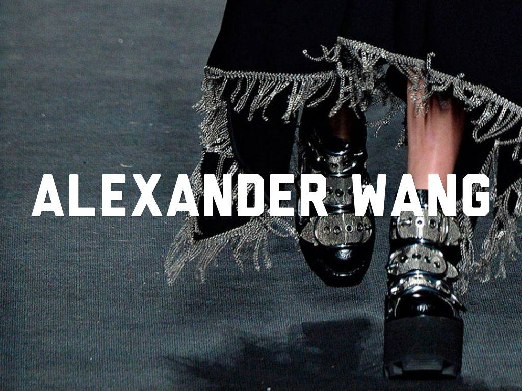 Alexander Wang 桌布 壁紙 — 模特兒雙腳特寫，穿著厚底黑色靴子，帶有銀色鏈條和流蘇，在黑暗的T台上行走。