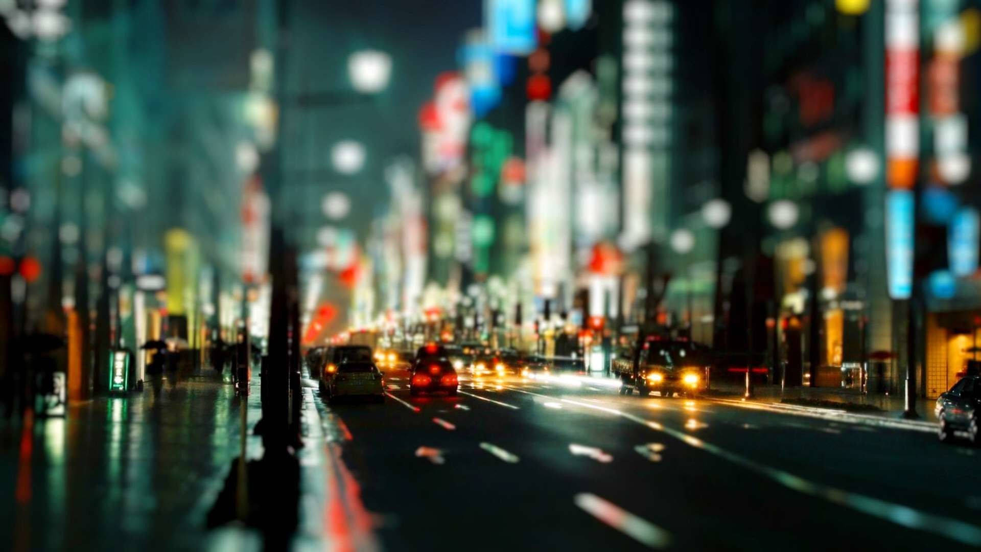 東京 桌布 壁紙 — 模糊的夜間城市街道，帶有發光的霓虹燈和流動的車頭燈，營造出夢幻般的城市隧道效果。