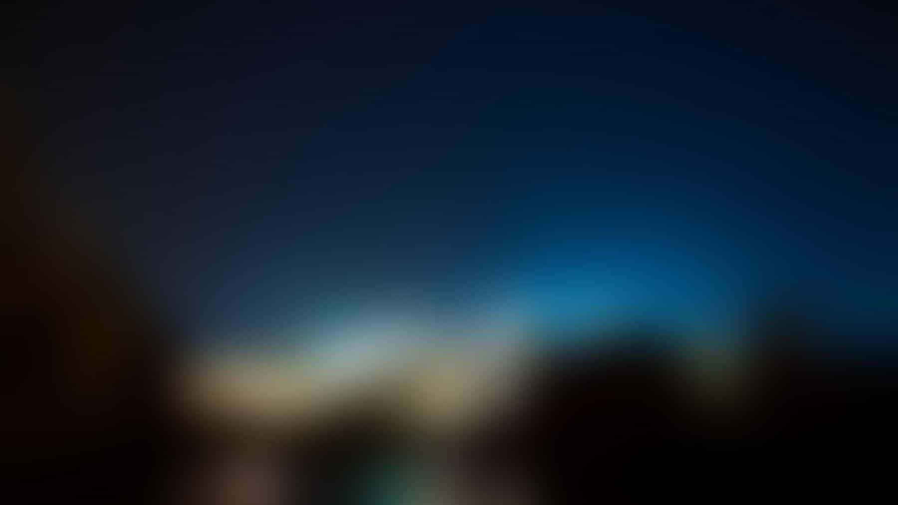 Blur 桌布 壁紙 — 模糊的漸變天空從深藍色過渡到柔和青色，籠罩在遠山暗影之上。
