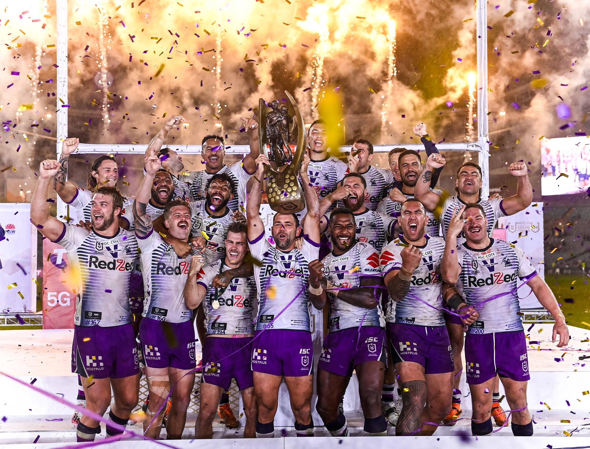 Nrl 桌布 壁紙 — 橄欖球聯賽隊伍在夜晚的金色紙屑和煙火中高舉獎盃慶祝勝利。