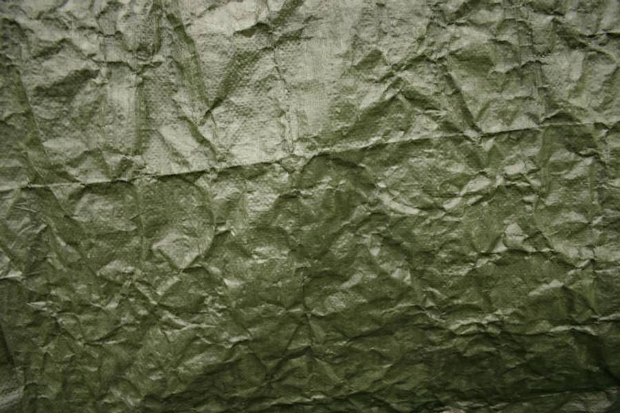 material desktop 桌布 壁紙 — 橄欖綠色皺摺防水布料的特寫，帶有紋理摺痕和柔和光線下的微妙光澤。