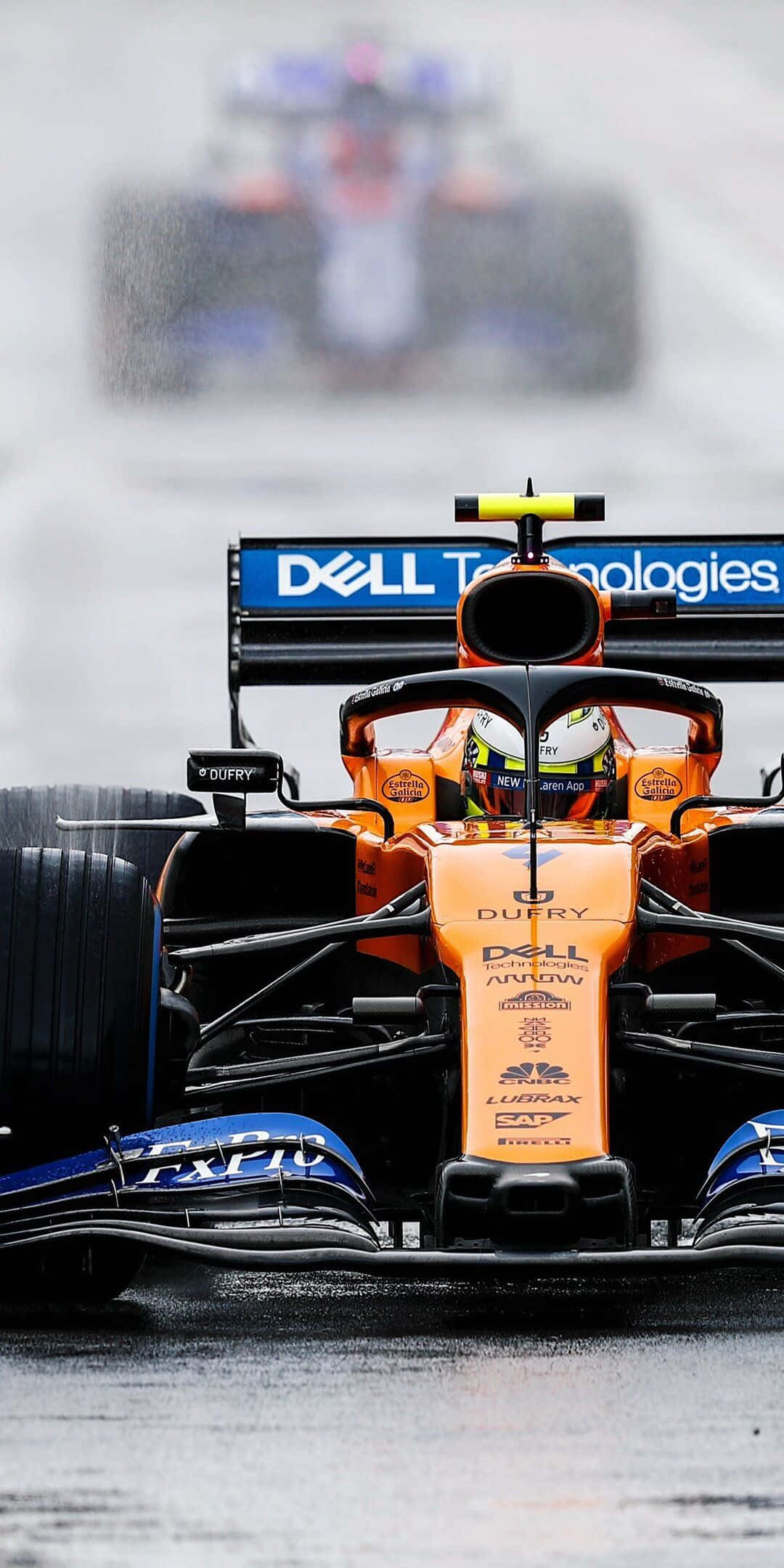 F1 2016 桌布 壁紙 — 橙色和藍色一級方程式賽車在濕滑賽道上高速行駛，水花四濺，背景中另一輛賽車模糊不清的特寫。