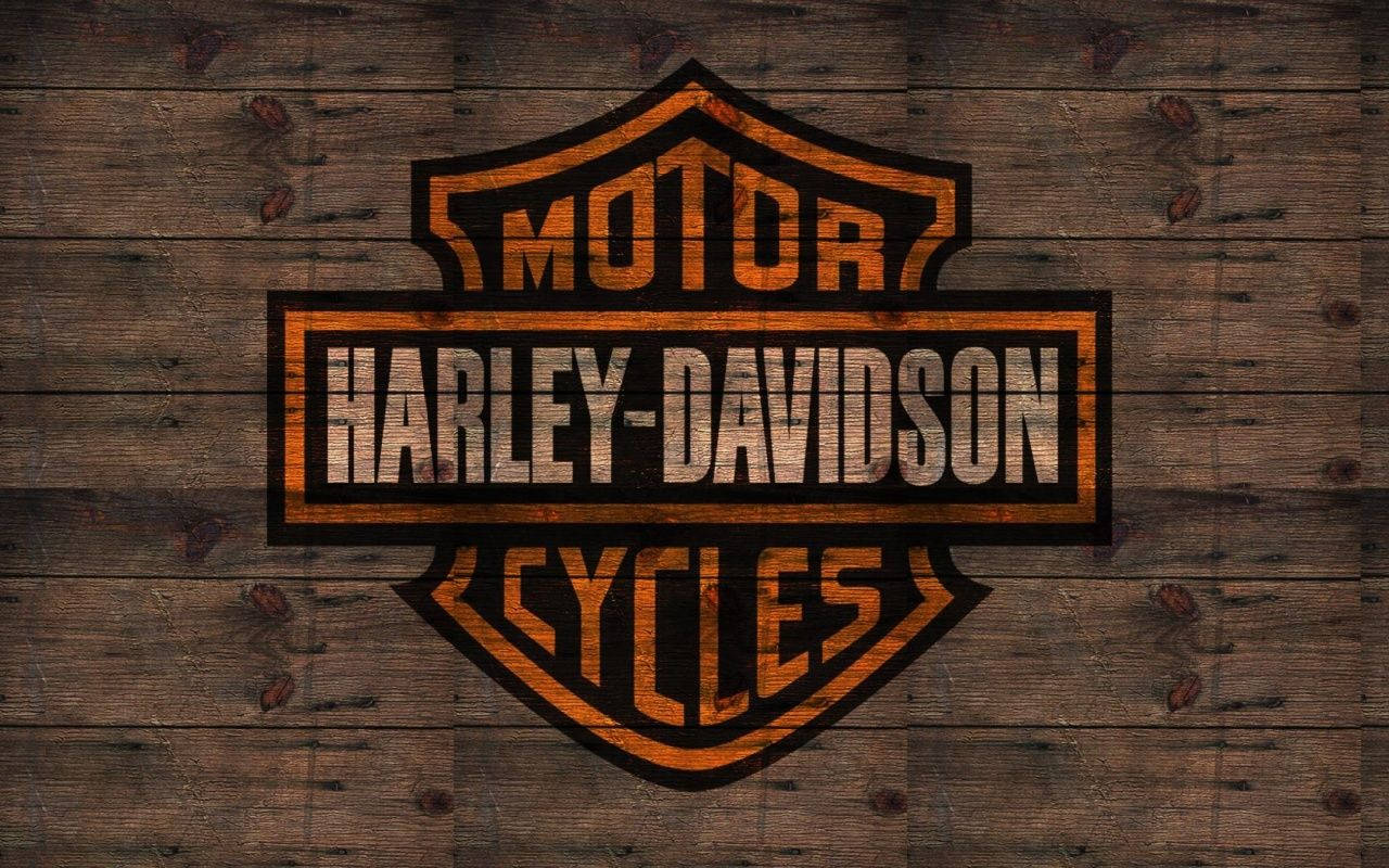 Harley 桌布 壁紙 — 橙色和黑色的Harley-Davidson標誌在風化的木板上，可見木紋和節疤。