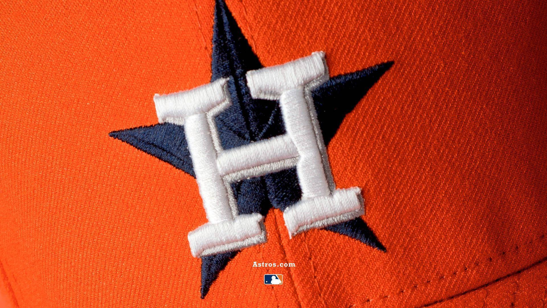 Astros 桌布 壁紙 — 橙色布料上，海軍藍星星上方帶有白色刺繡H的休士頓太空人棒球帽標誌特寫。