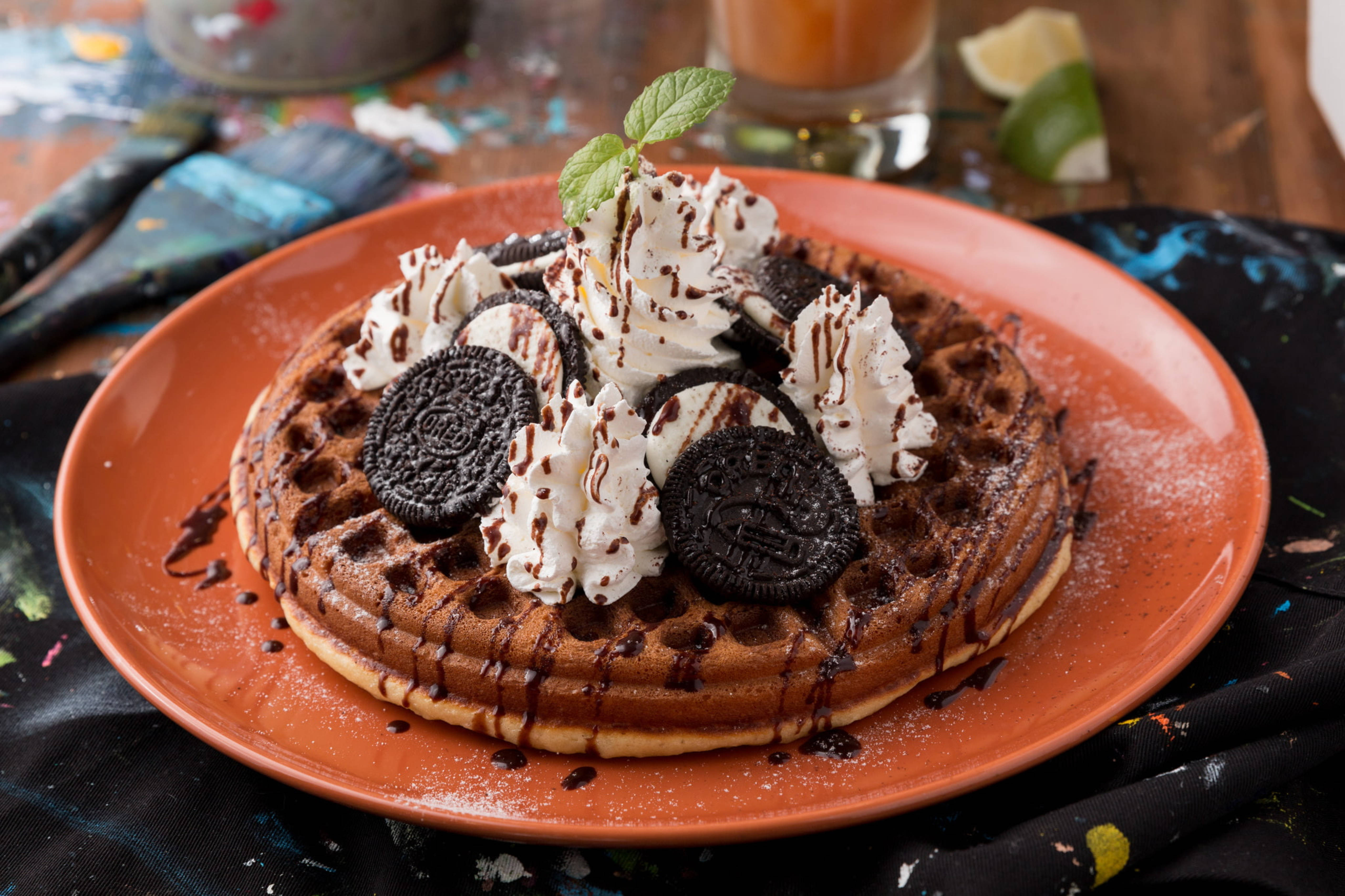Waffle 桌布 壁紙 — 橙色盤子上的巧克力鬆餅，上面有鮮奶油、Oreo 餅乾和巧克力醬。