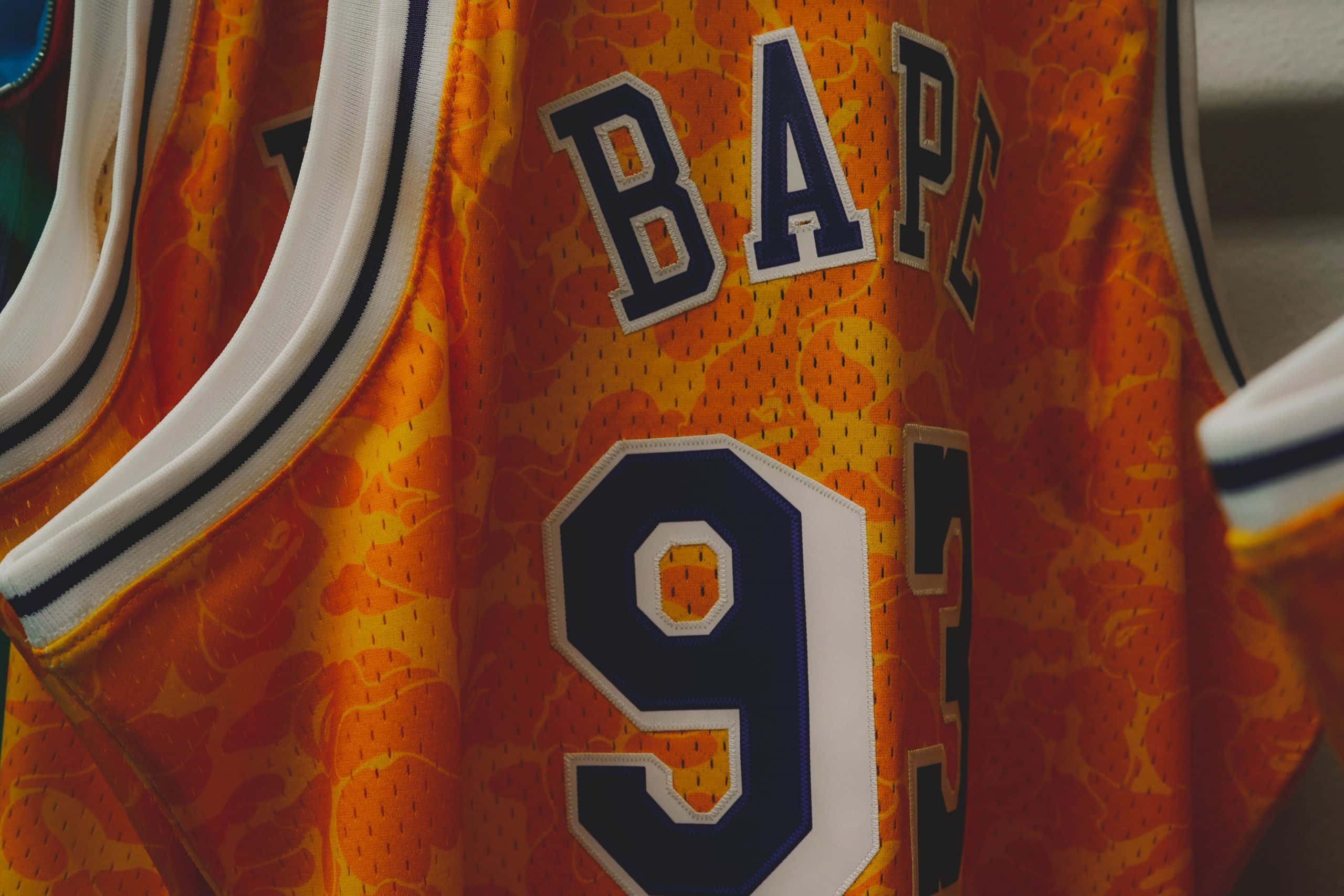 Red Bape 桌布 壁紙 — 橙色籃球球衣特寫，上面有 'BAPE' 和數字 '93'，以粗體海軍藍和白色字體呈現。