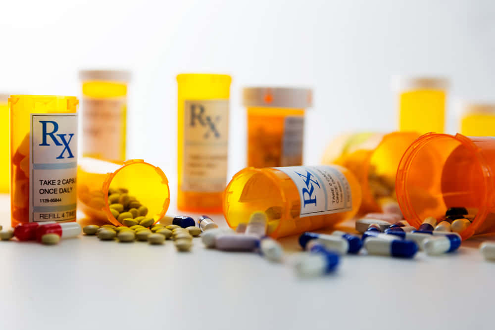 medicine 桌布 壁紙 — 橙色處方藥瓶翻倒在白色表面上，灑出色彩繽紛的藥丸和膠囊。