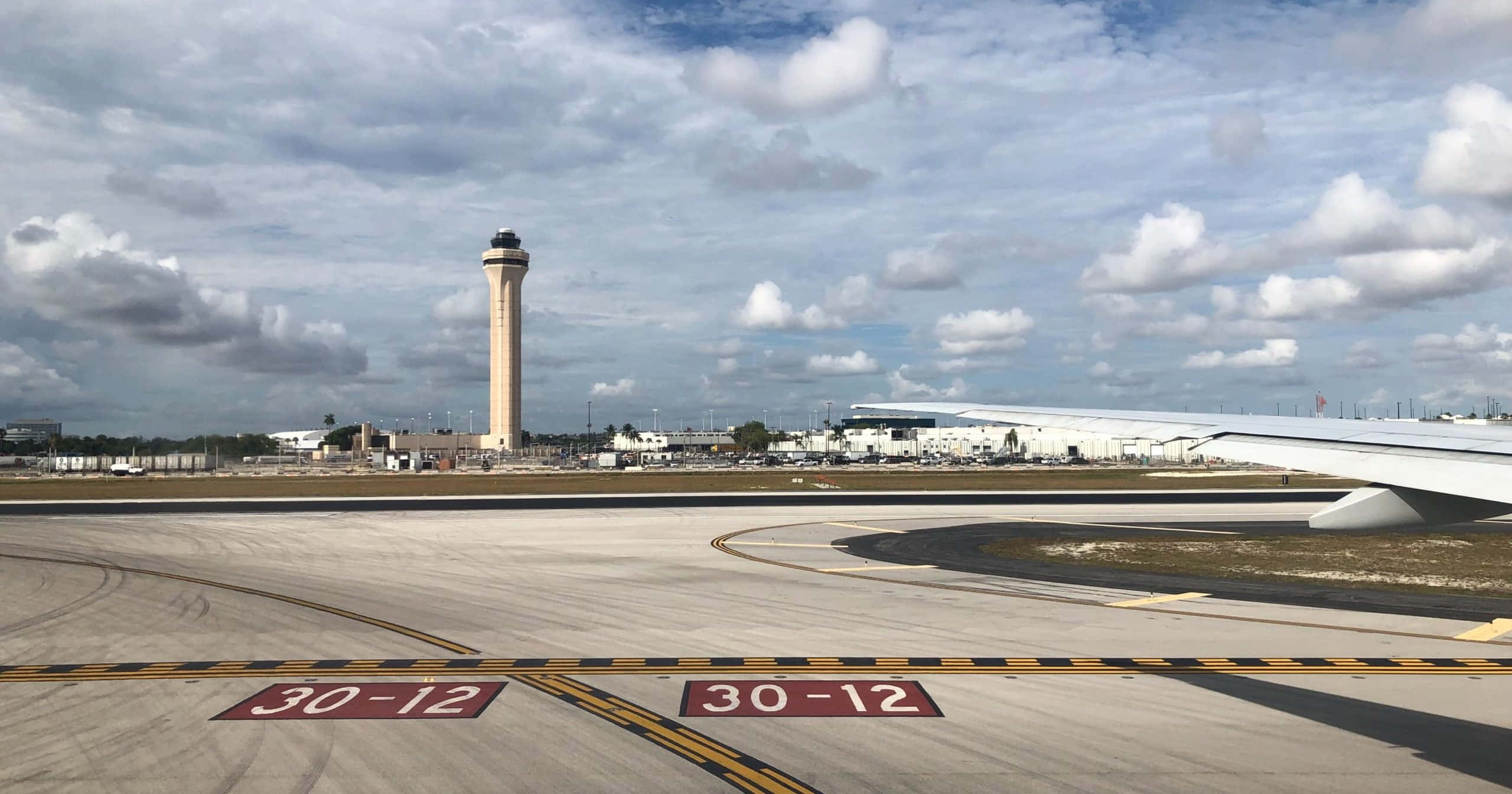 Runway 桌布 壁紙 — 機場停機坪的廣角鏡頭，設有控制塔和飛機機翼，天空多雲。