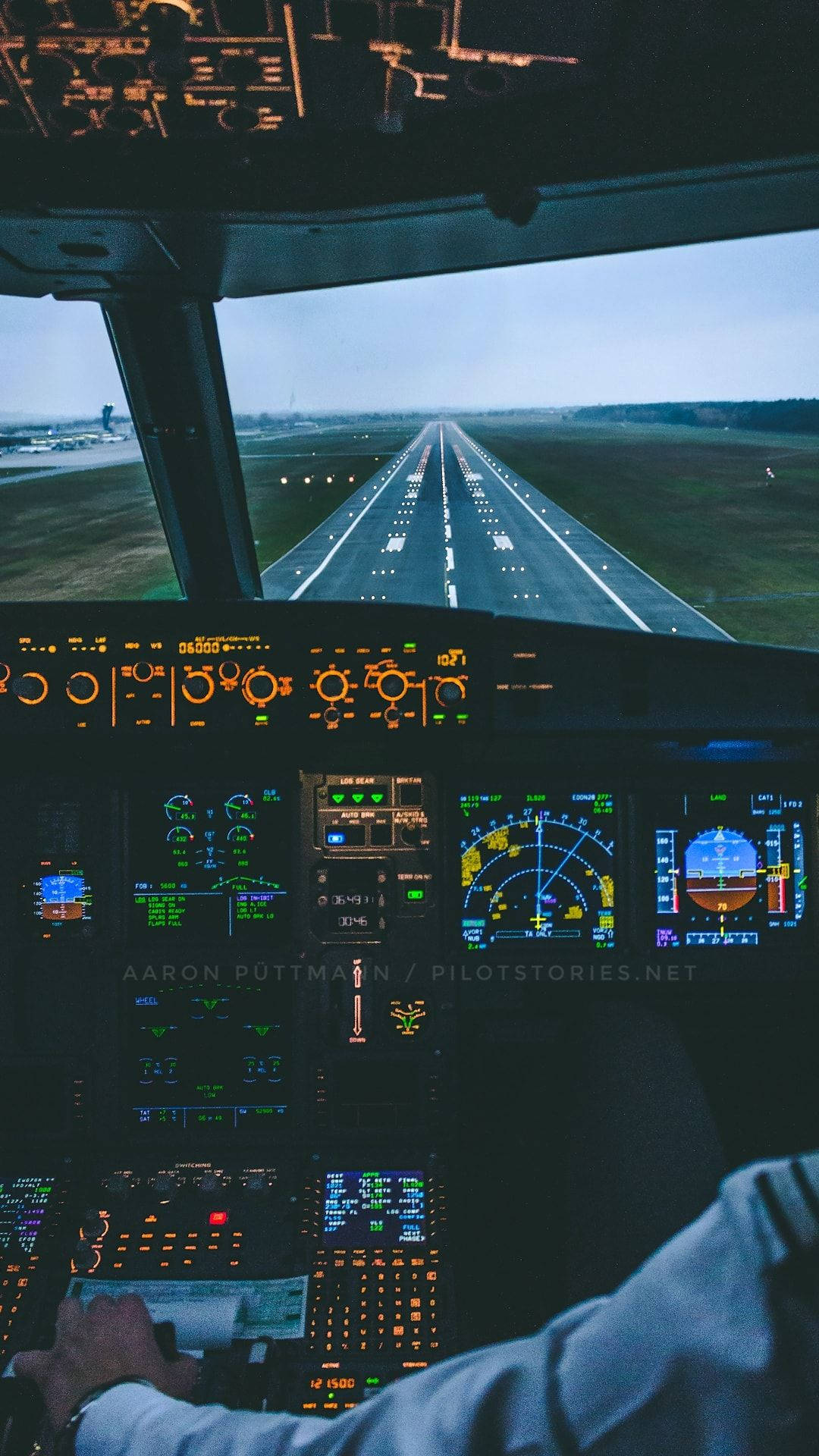 Runway 桌布 壁紙 — 機師的手握著控制桿，駕駛艙儀表板在暮色天空下的跑道前閃爍著儀器燈光。