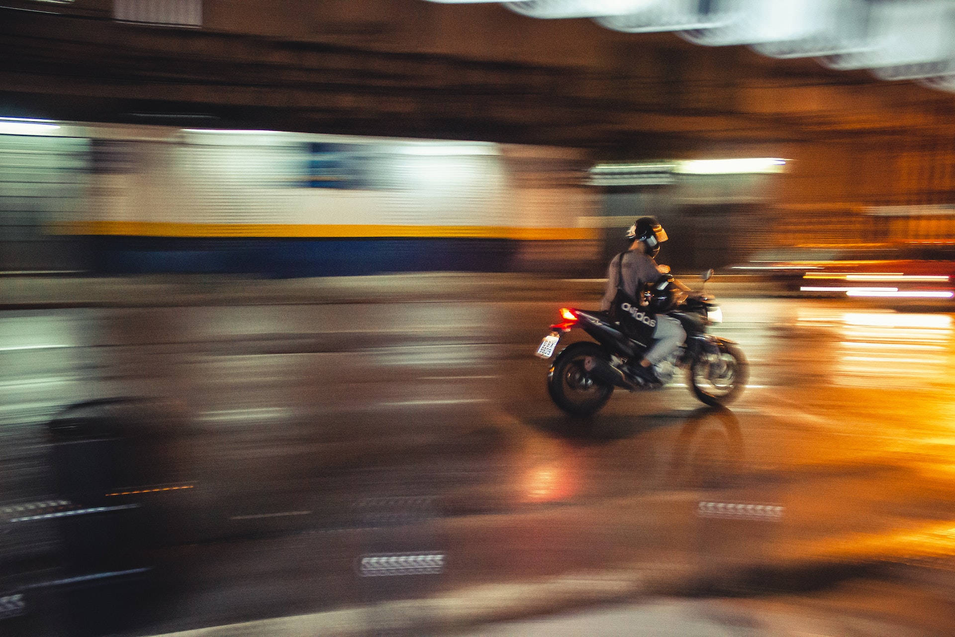 Speed 桌布 壁紙 — 機車騎士在雨夜的城市街道上奔馳，燈光模糊，濕漉漉的路面反射著光影。