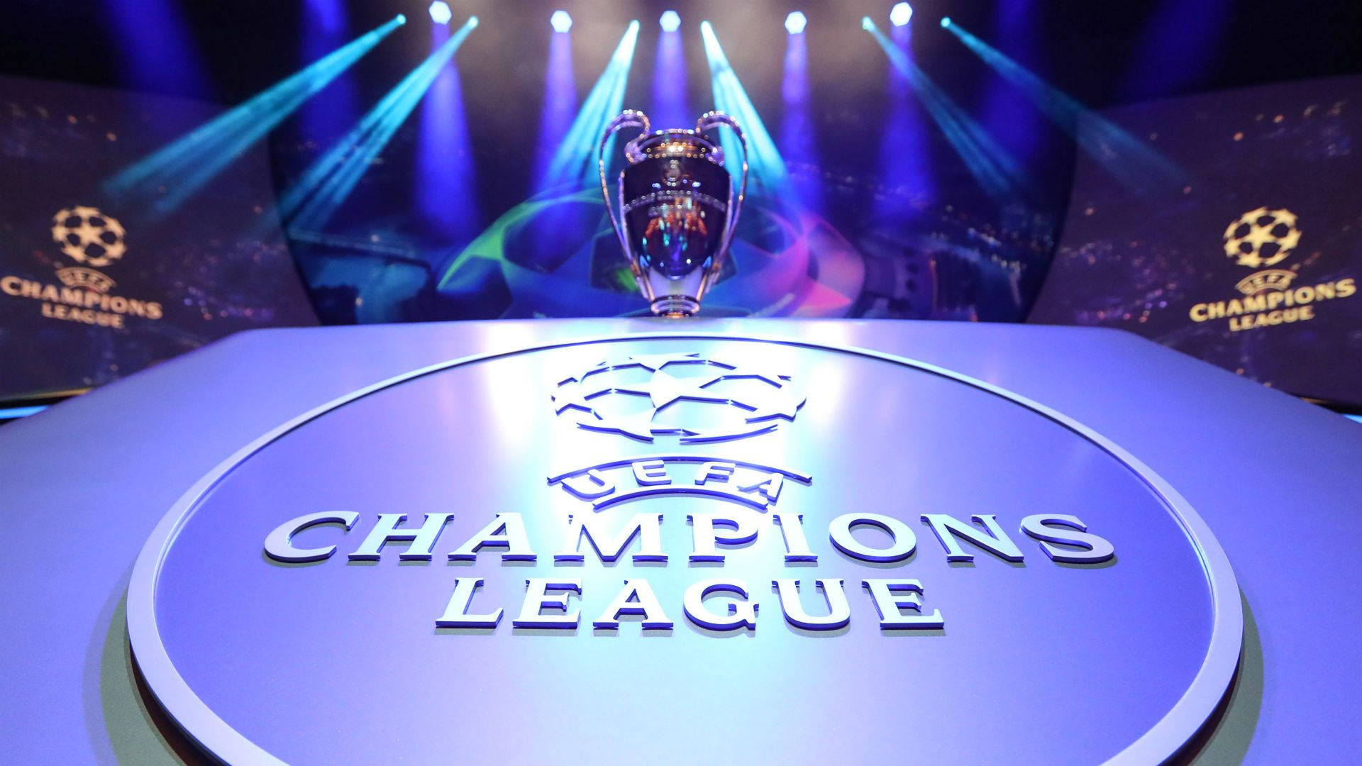 Uefa 桌布 壁紙 — 歐冠獎盃在球場的藍色聚光燈下，在品牌底座上閃閃發光。