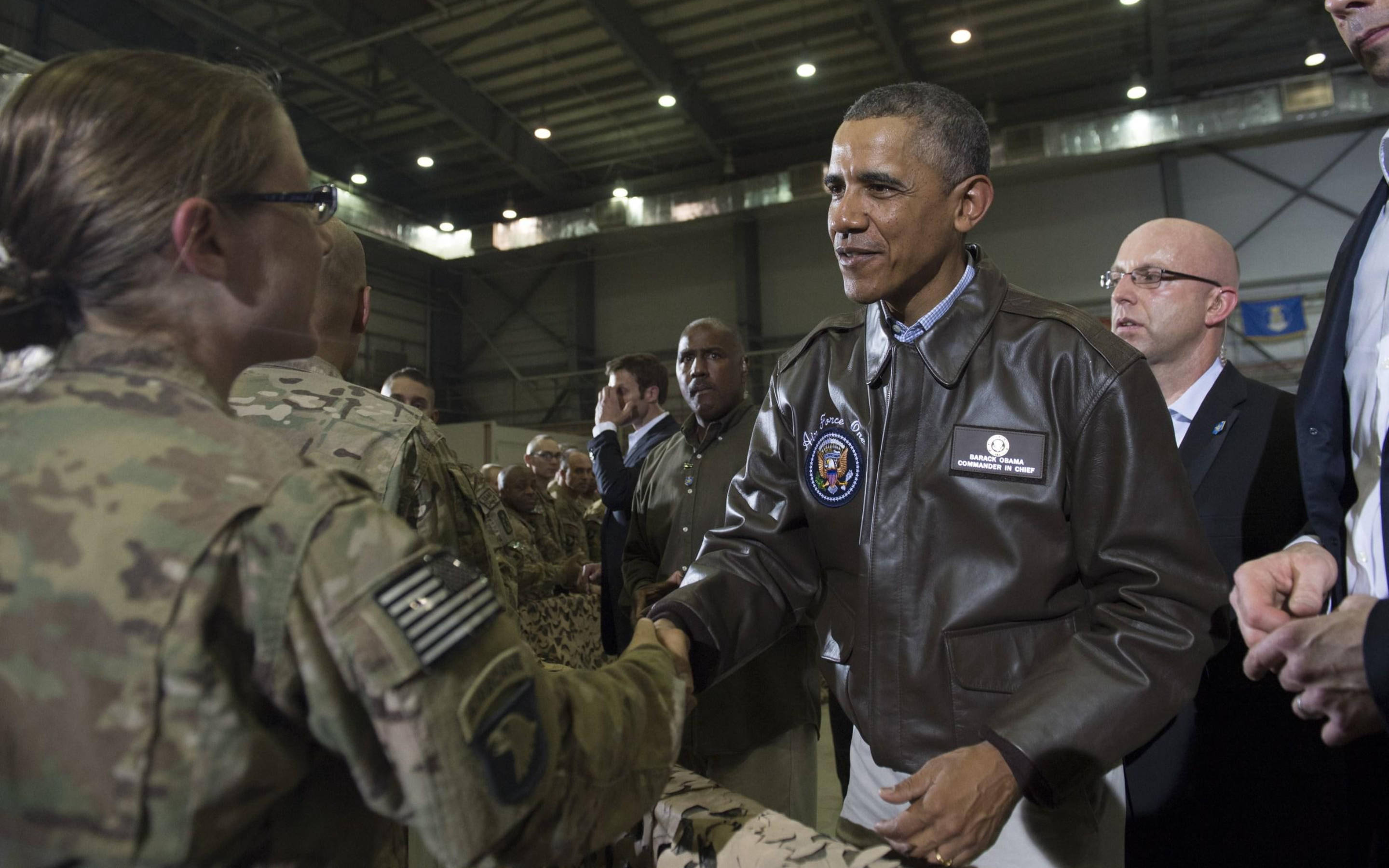 Barack 桌布 壁紙 — 歐巴馬總統在一個擠滿軍方人員和官員的機庫中與一名士兵握手。