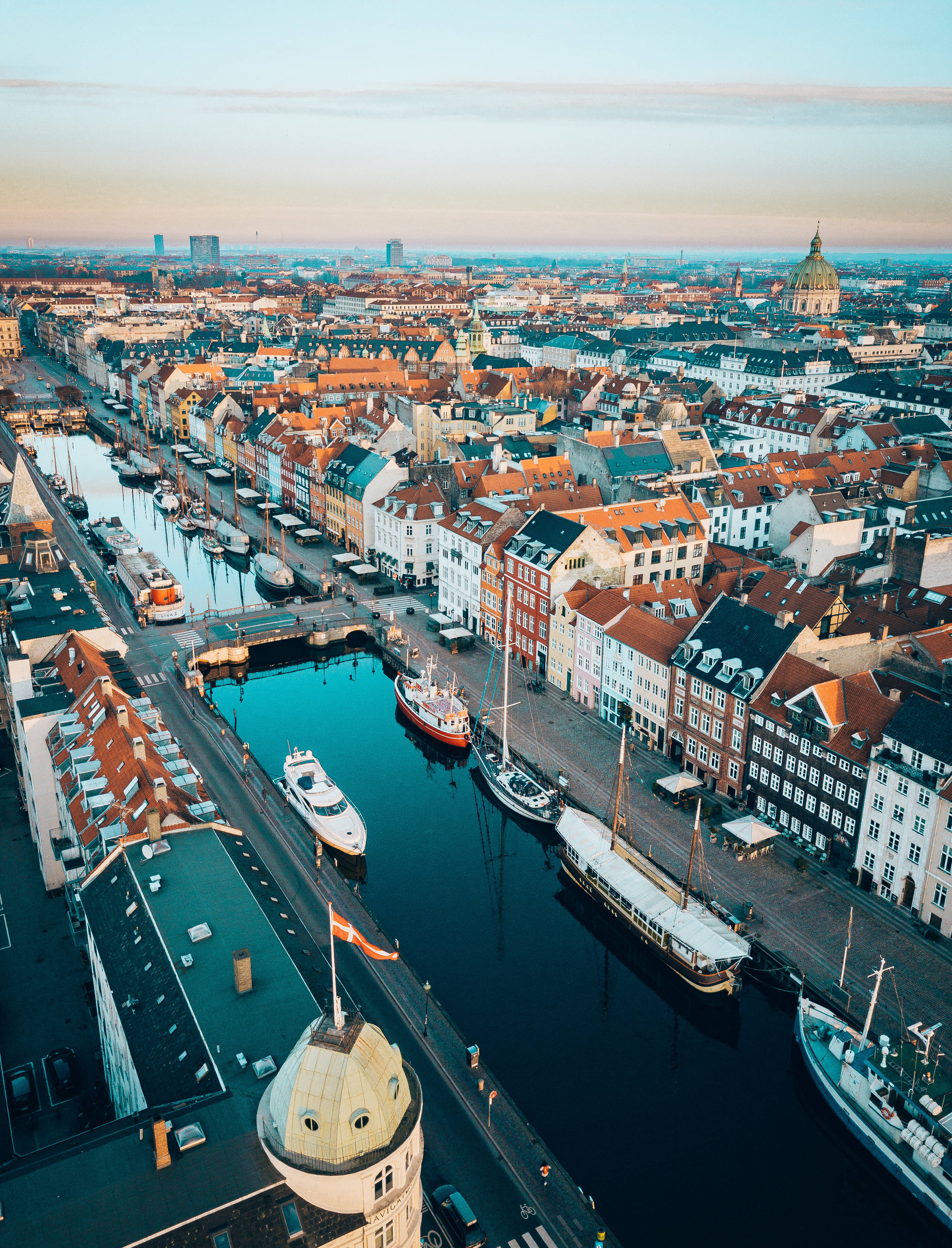 Denmark 桌布 壁紙 — 歐洲城市日落時分，色彩繽紛的歷史建築沿運河排列，河上有船隻的鳥瞰圖。