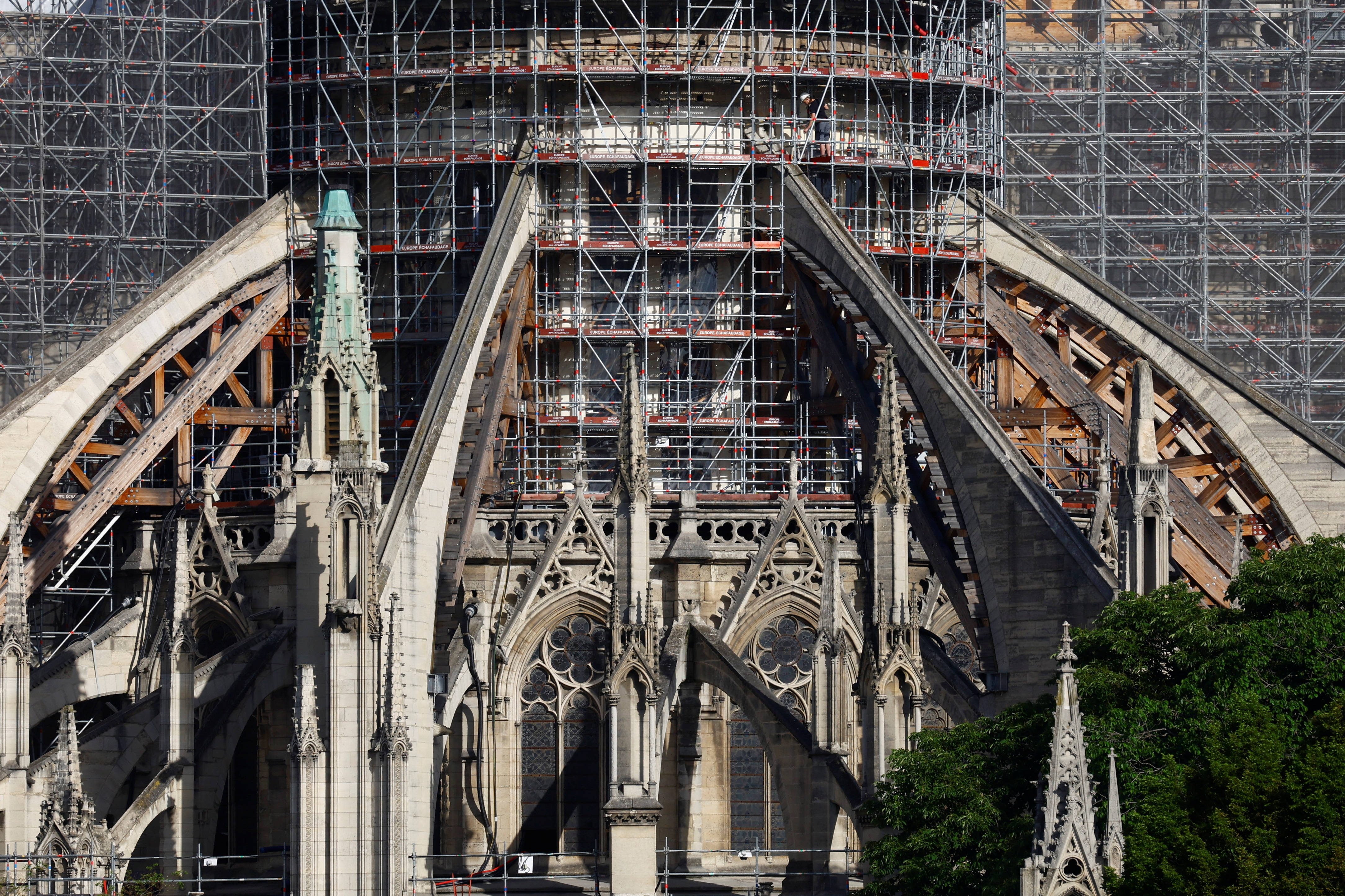 Notre Dame 桌布 壁紙 — 正在修復的哥德式大教堂，複雜的石拱門和鷹架映襯著晴朗的天空。
