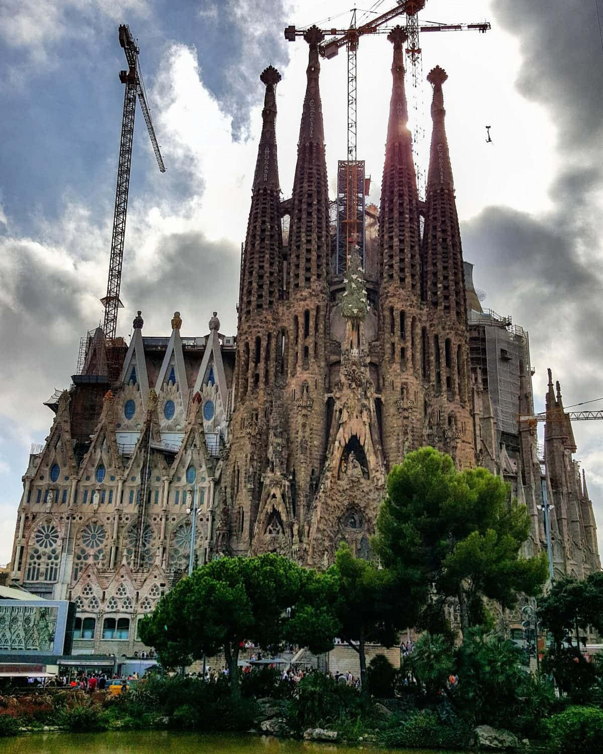 Beautiful Architecture 桌布 壁紙 — 正在建造中的宏偉聖家堂大教堂，高聳的尖塔和起重機映襯著多雲的天空。