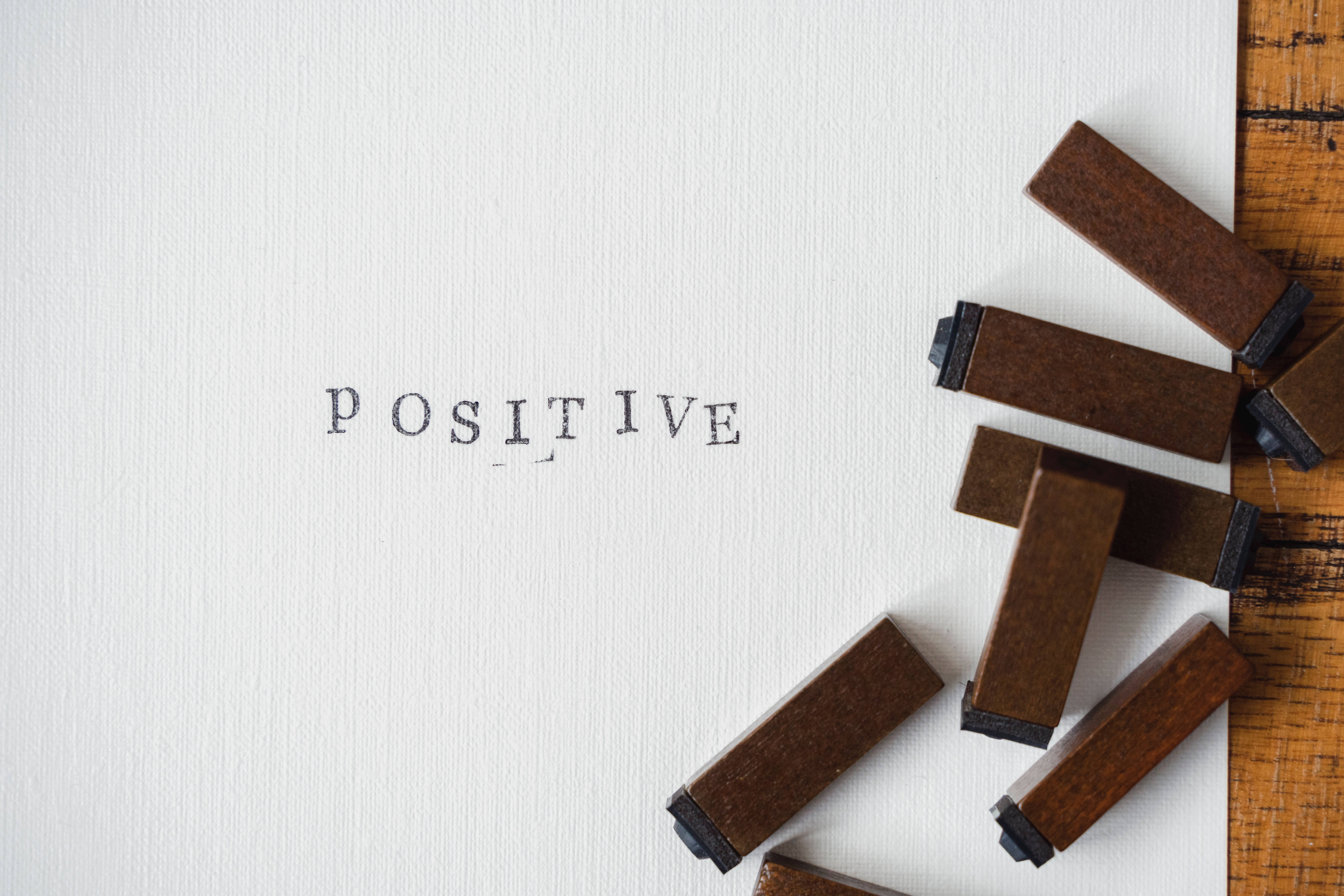Positive 桌布 壁紙 — 「正面」一詞以復古活版印刷印在帶有紋理的白色紙張上，周圍環繞著木製字塊。