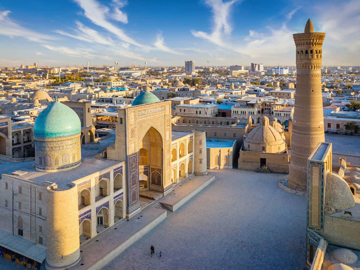 Uzbekistan 桌布 壁紙 — 歷史伊斯蘭建築的鳥瞰圖，擁有綠松石圓頂和宣禮塔，背景是明亮的藍天，下方是廣闊的城市景觀。