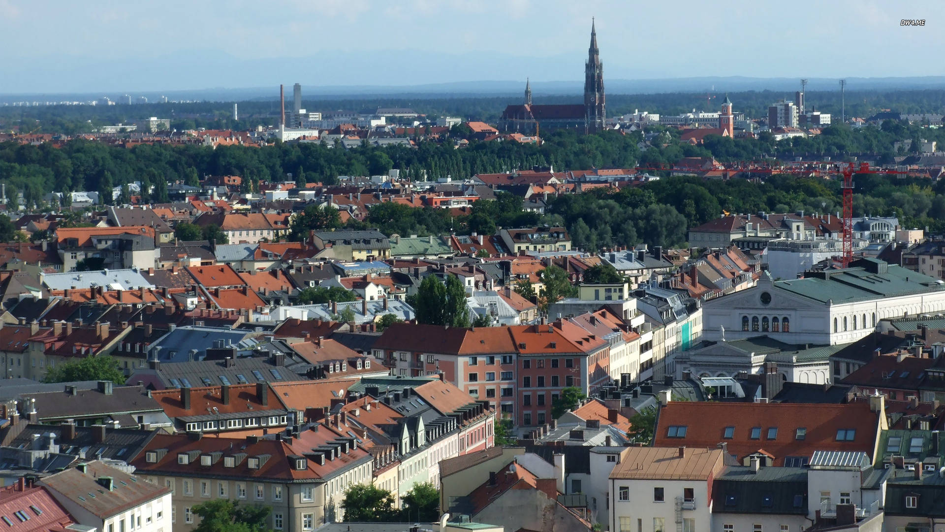 Munich 桌布 壁紙 — 歷史悠久的歐洲城市的鳥瞰圖，擁有紅瓦屋頂和一座突出的教堂尖塔，聳立在茂密的綠樹之上。