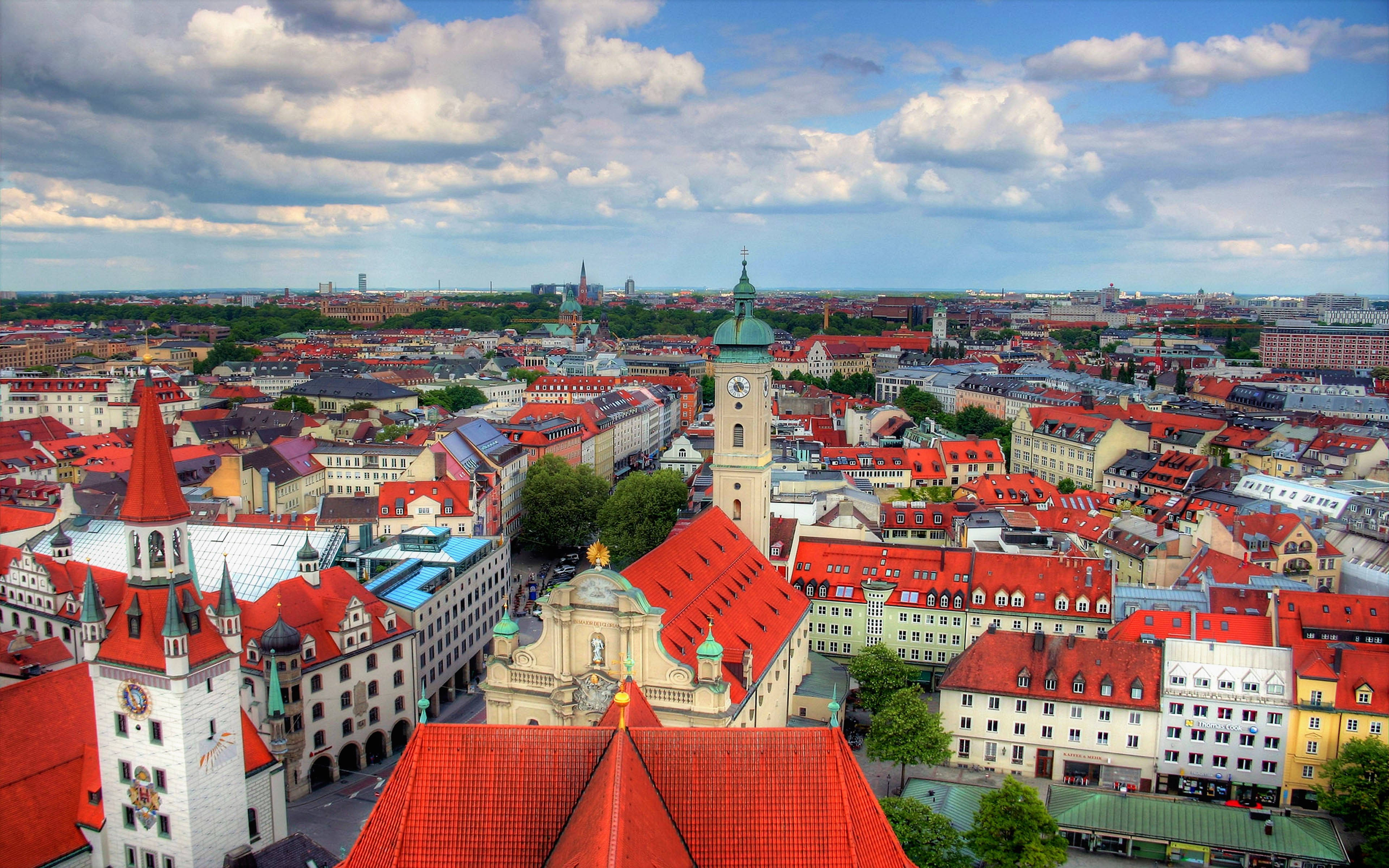 Munich 桌布 壁紙 — 歷史悠久的歐洲城市鳥瞰圖，擁有紅色瓦片屋頂和突出的鐘樓，天空部分多雲。
