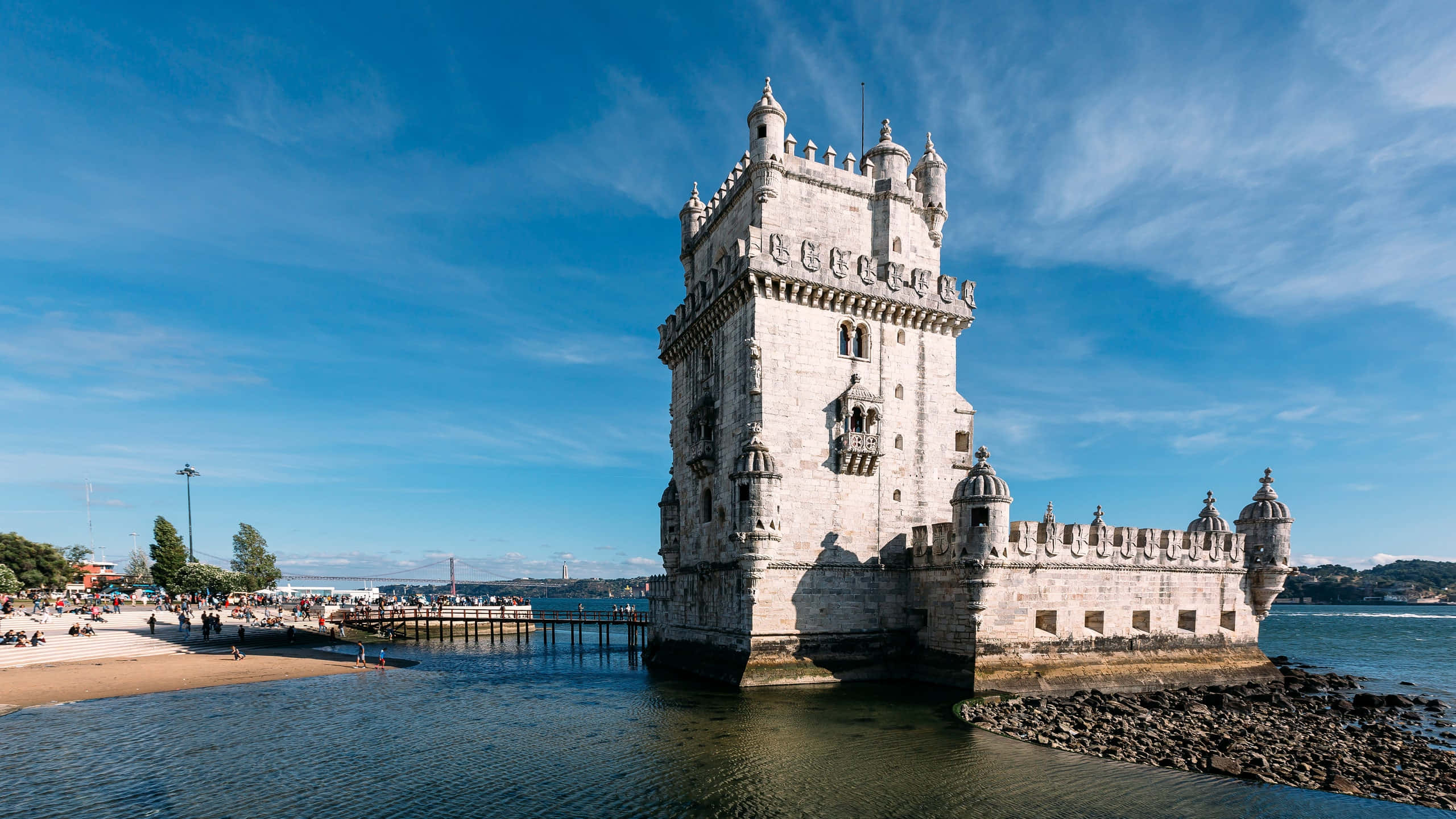 Portugal 桌布 壁紙 — 歷史悠久的貝倫塔在明亮的藍天和縷縷白雲下，雄偉地矗立在水面上。