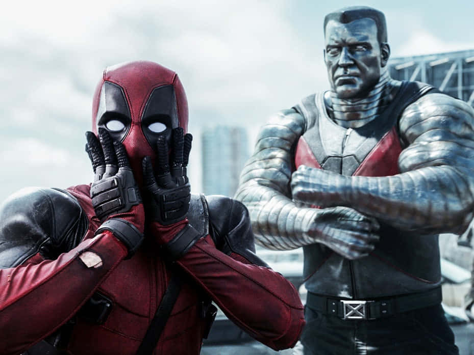 Deadpool And Colossus 桌布 壁紙 — 死侍在陰天下站在城市屋頂上，在嚴肅的機堡旁邊假裝驚恐地遮住臉。
