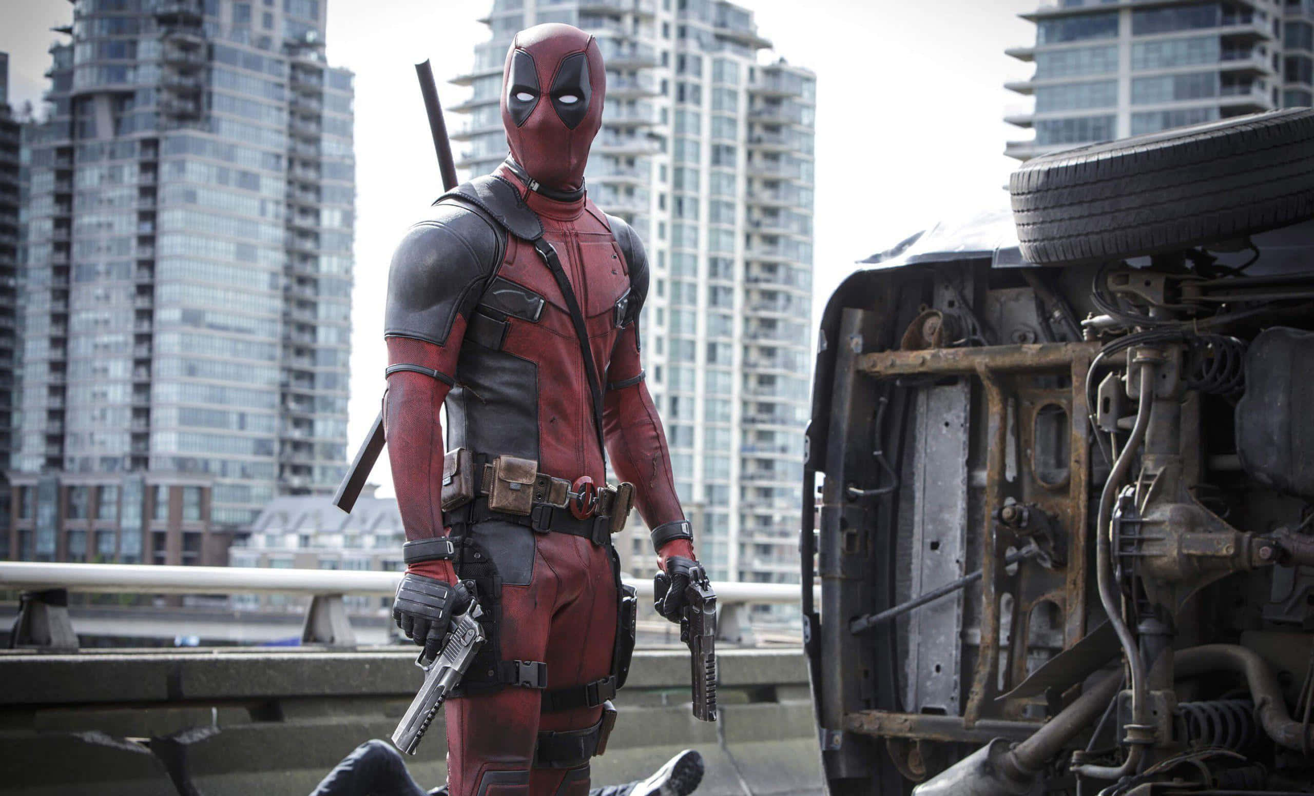 Deadpool 2 桌布 壁紙 — 死侍自信地站在城市天橋上，旁邊是一輛損毀的汽車，身後摩天大樓聳立。