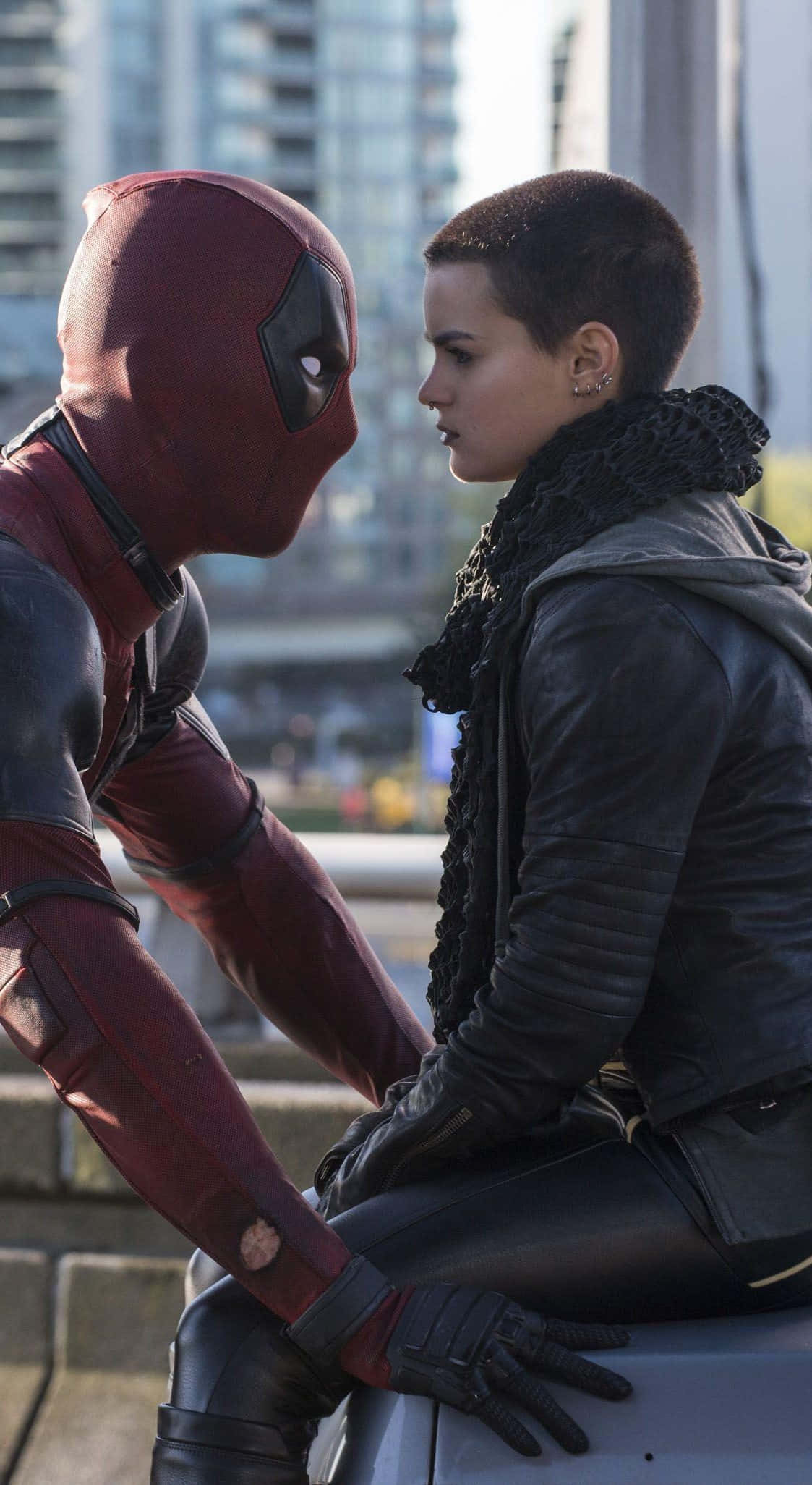 Negasonic Teenage Warhead 桌布 壁紙 — 死侍身穿紅色戰衣，在都市屋頂上與一位短髮、身穿黑色皮衣的女子對峙。