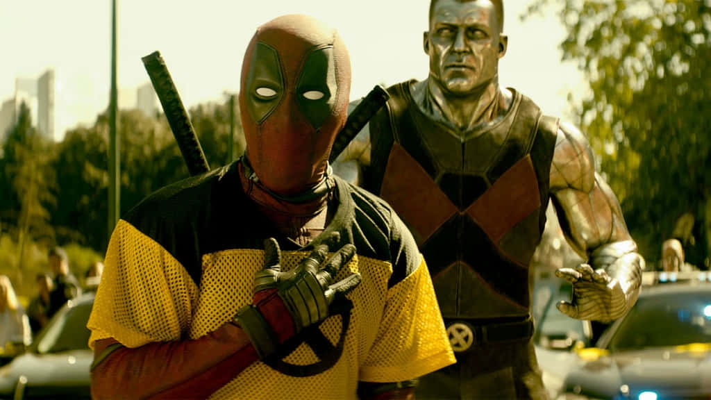 Deadpool And Colossus 桌布 壁紙 — 死侍身穿黃色網眼衫、戴著面具，與身穿裝甲服的機堡一起站在城市街道的車流中。
