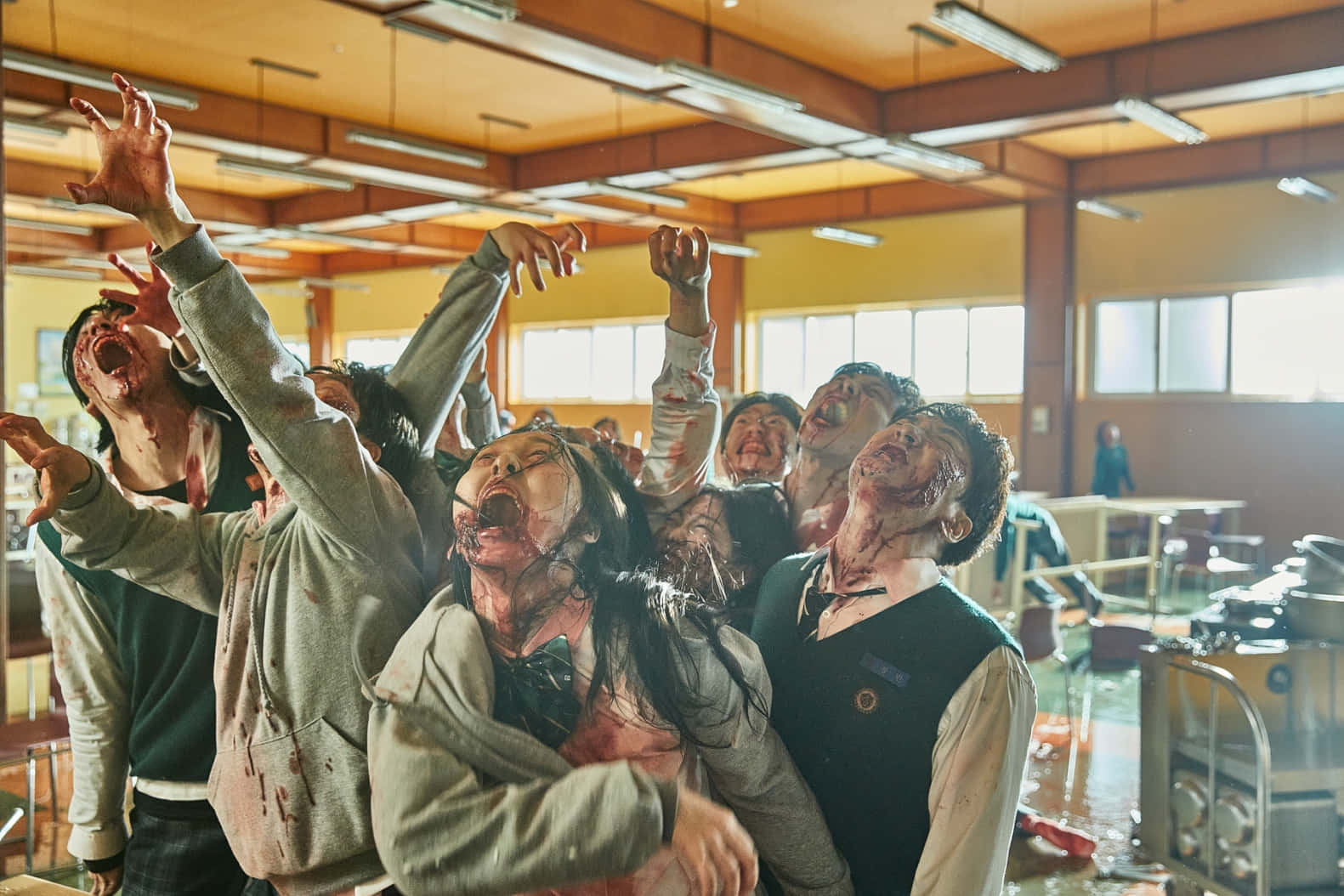 All Of US Are Dead 桌布 壁紙 — 殭屍滿臉鮮血、高舉雙臂，在日光下的混亂學校餐廳中尖叫。