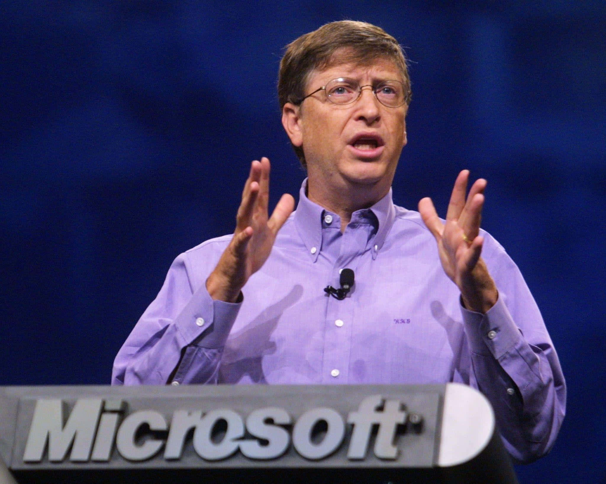 Bill Gates 桌布 壁紙 — 比爾·蓋茲在微軟活動中熱情演講，身穿紫色鈕扣襯衫，背景為藍色。