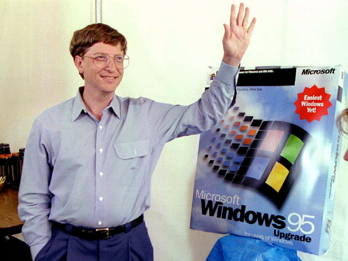 Windows 95 動態圖 桌布 壁紙 — 比爾·蓋茲微笑並揮手，旁邊是帶有彩色像素標誌的 Microsoft Windows 95 升級盒。