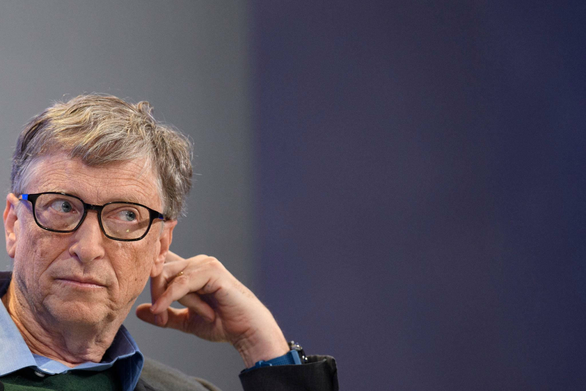 gates 桌布 壁紙 — 比爾蓋茲沉思姿勢的特寫，手靠近下巴，背景為模糊的藍灰色。