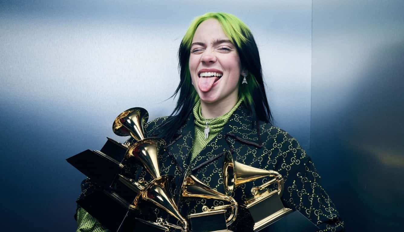 Billie Eilish Laptop 桌布 壁紙 — 比莉·艾利許伸出舌頭狂笑，手持多個葛萊美獎座，背景是酷炫藍色漸變。