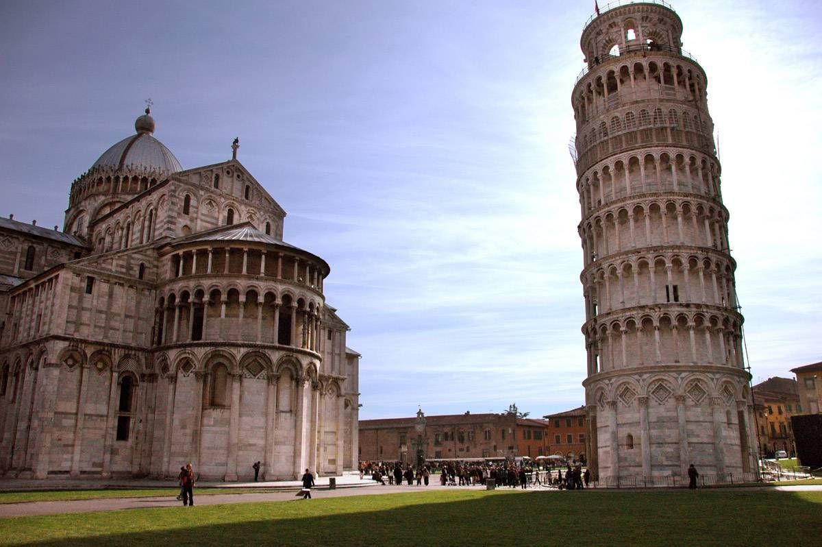 Tuscany 桌布 壁紙 — 比薩斜塔傾斜地矗立在比薩大教堂旁邊，天空湛藍，草地上有遊客。