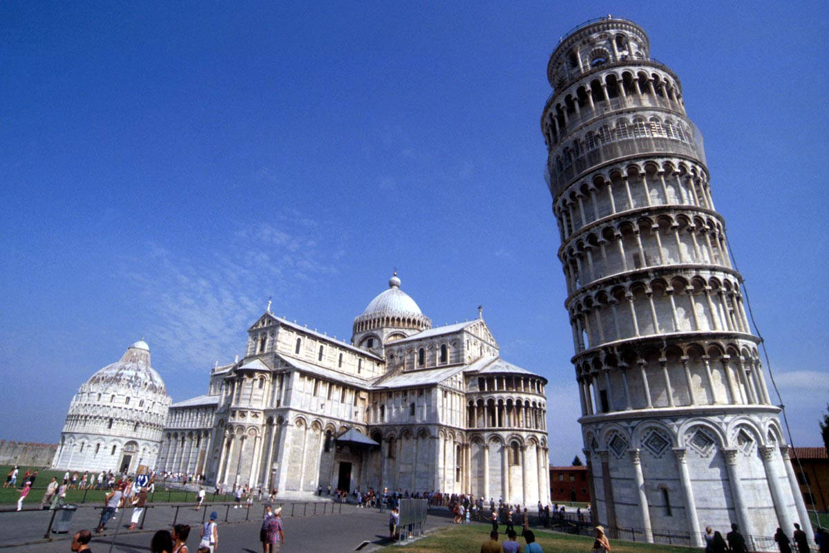 Tuscany 桌布 壁紙 — 比薩斜塔傾斜地矗立在比薩大教堂旁邊，天空清澈湛藍，周圍聚集著遊客。
