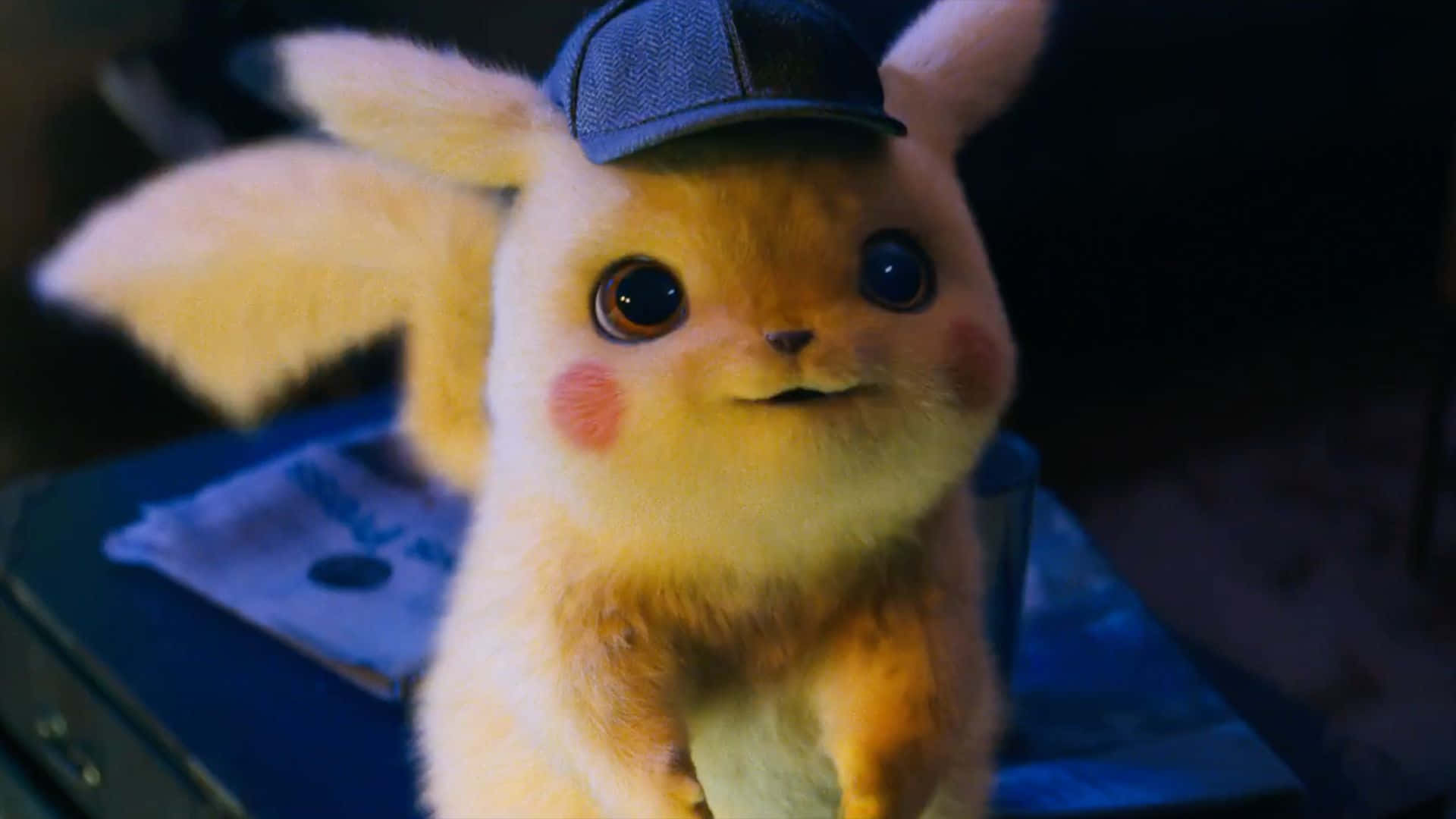 Pokemon Movies 桌布 壁紙 — 毛茸茸的皮卡丘戴著偵探帽，在昏暗燈光下睜大好奇的眼睛的特寫。