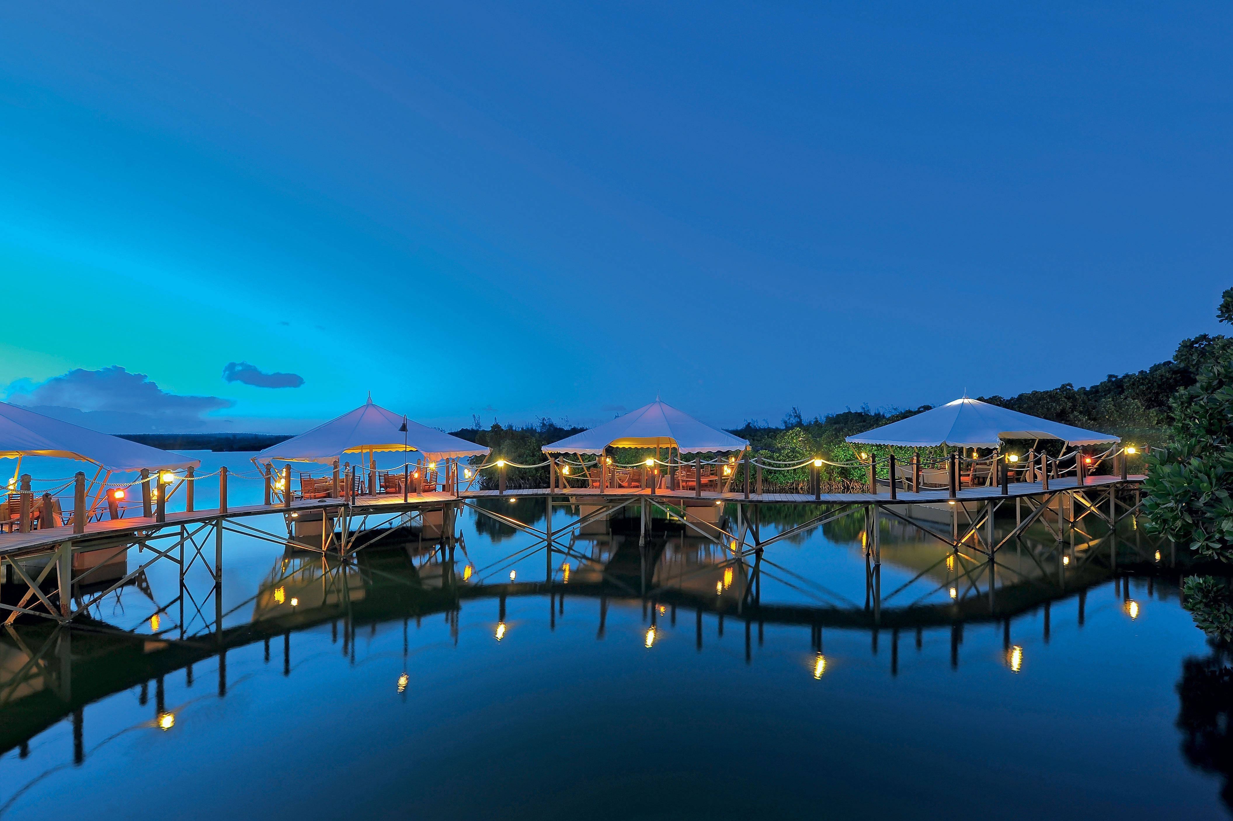 Mauritius 桌布 壁紙 — 水上亭閣帶有發光燈光，在深藍色暮色天空下平靜的水面上反射。