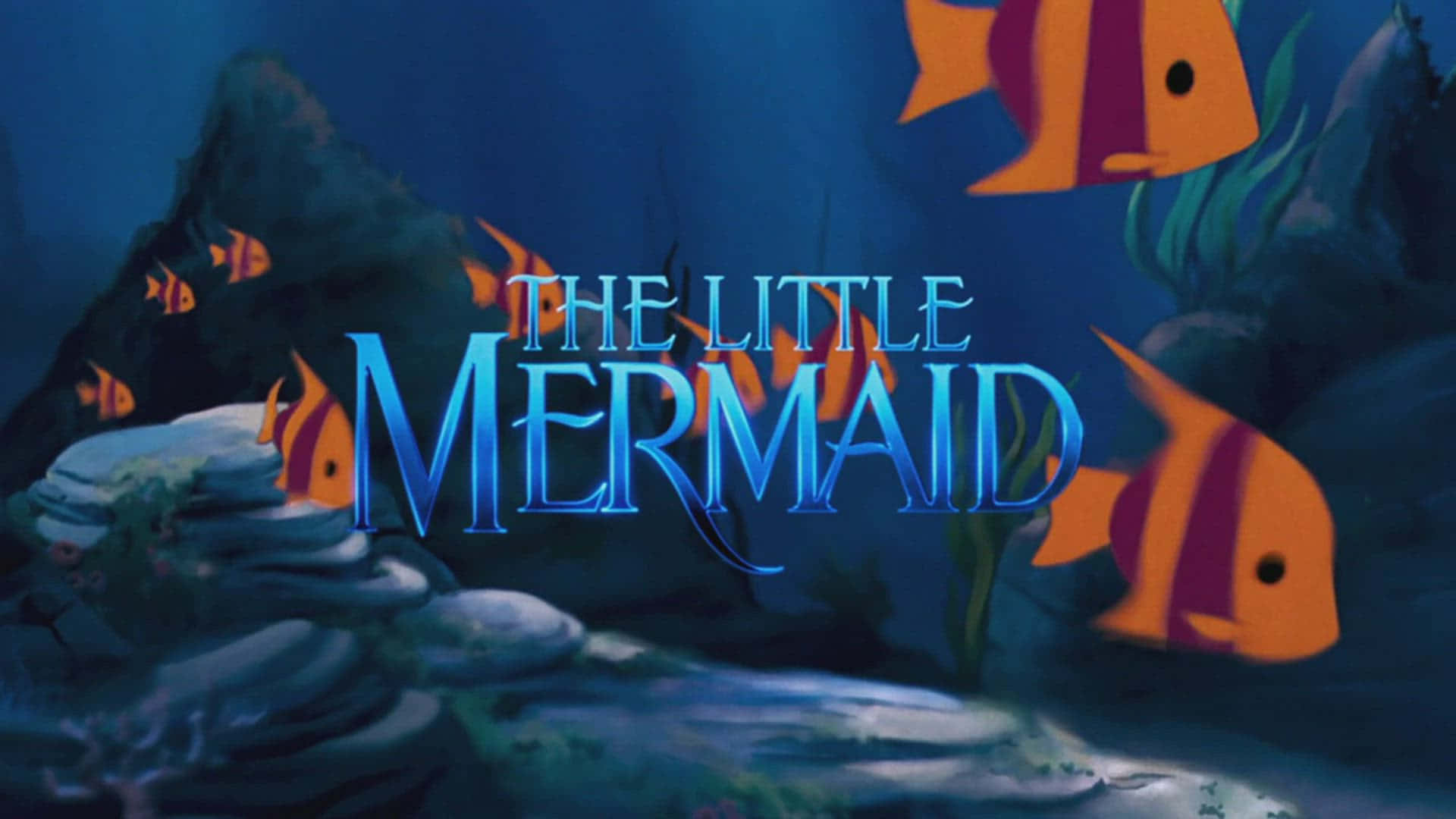 The Little Mermaid 桌布 壁紙 — 水底場景，有橙色和紫色條紋魚在珊瑚和岩石附近游動，並有發光藍色標題文字。